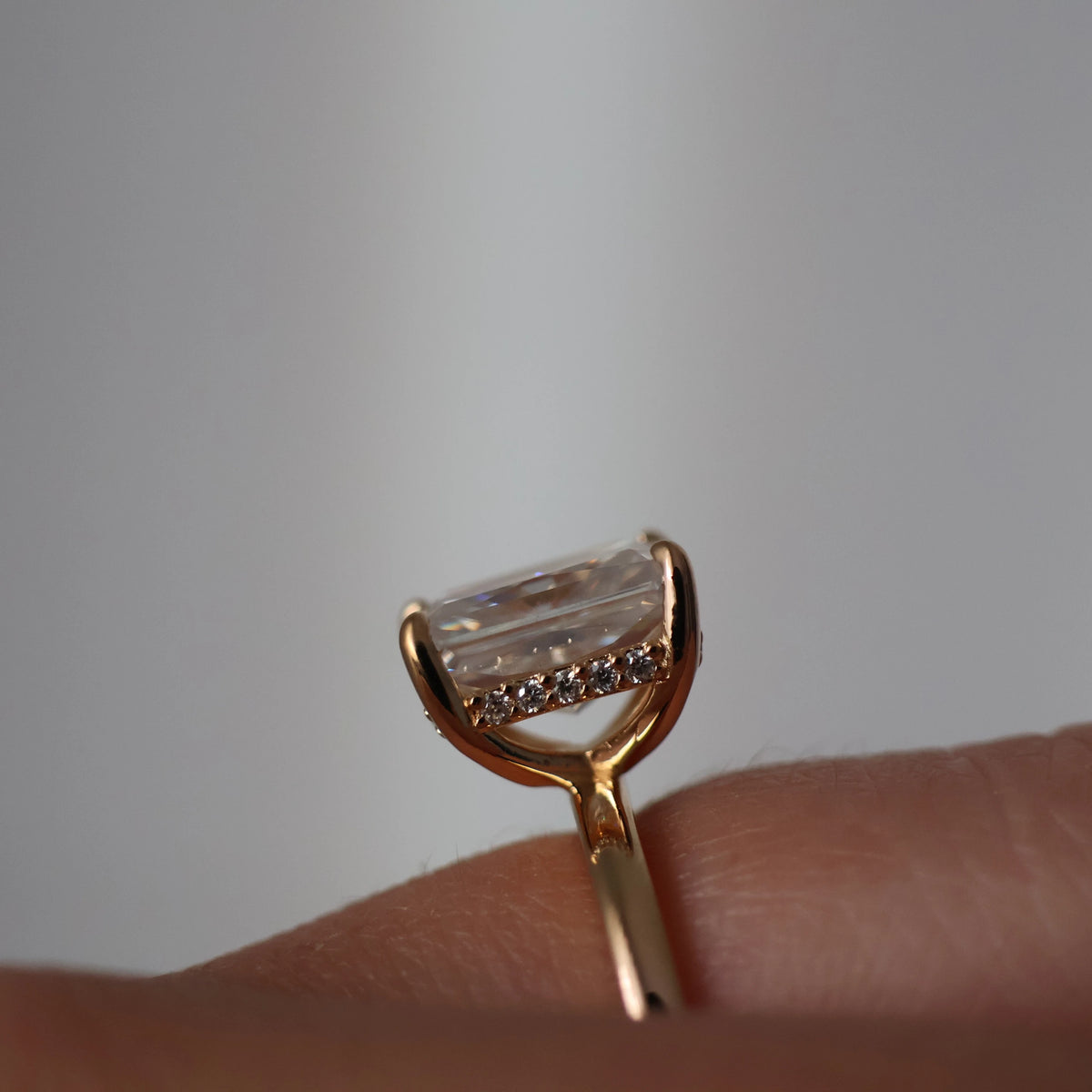 Side view of a 3 carat radiant cut moissanite ring in 14k gold filled with hidden halo