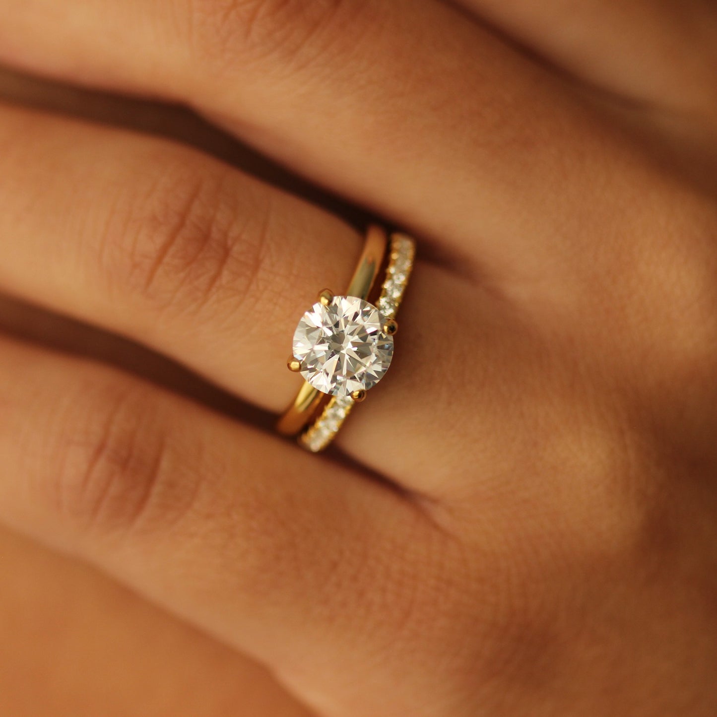 2 ct round gold engagement ring and half pave ring on hand