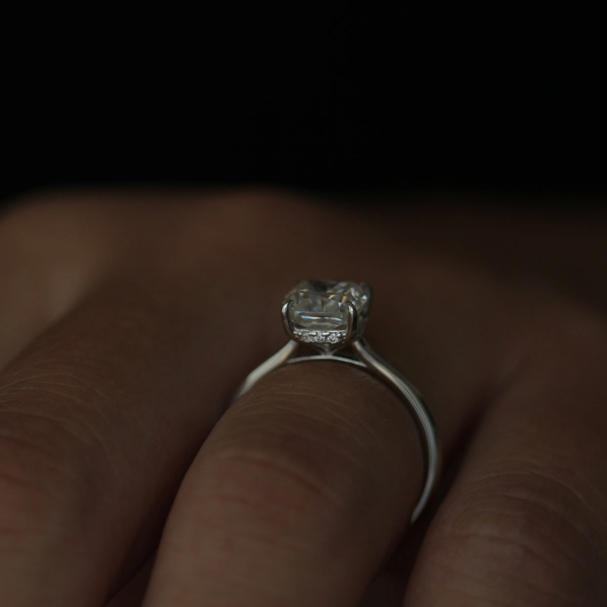 front view of a 2 carat cushion cut moissanite engagement ring set in a silver band