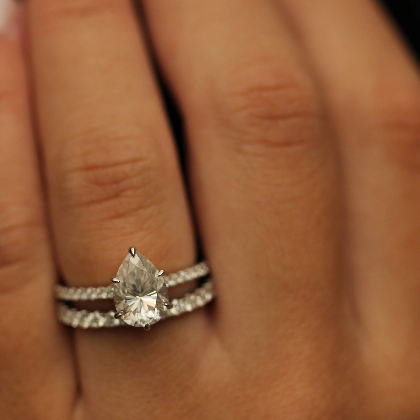 2 carat pear cut moissanite engagement ring and moissanite pave band on hand
