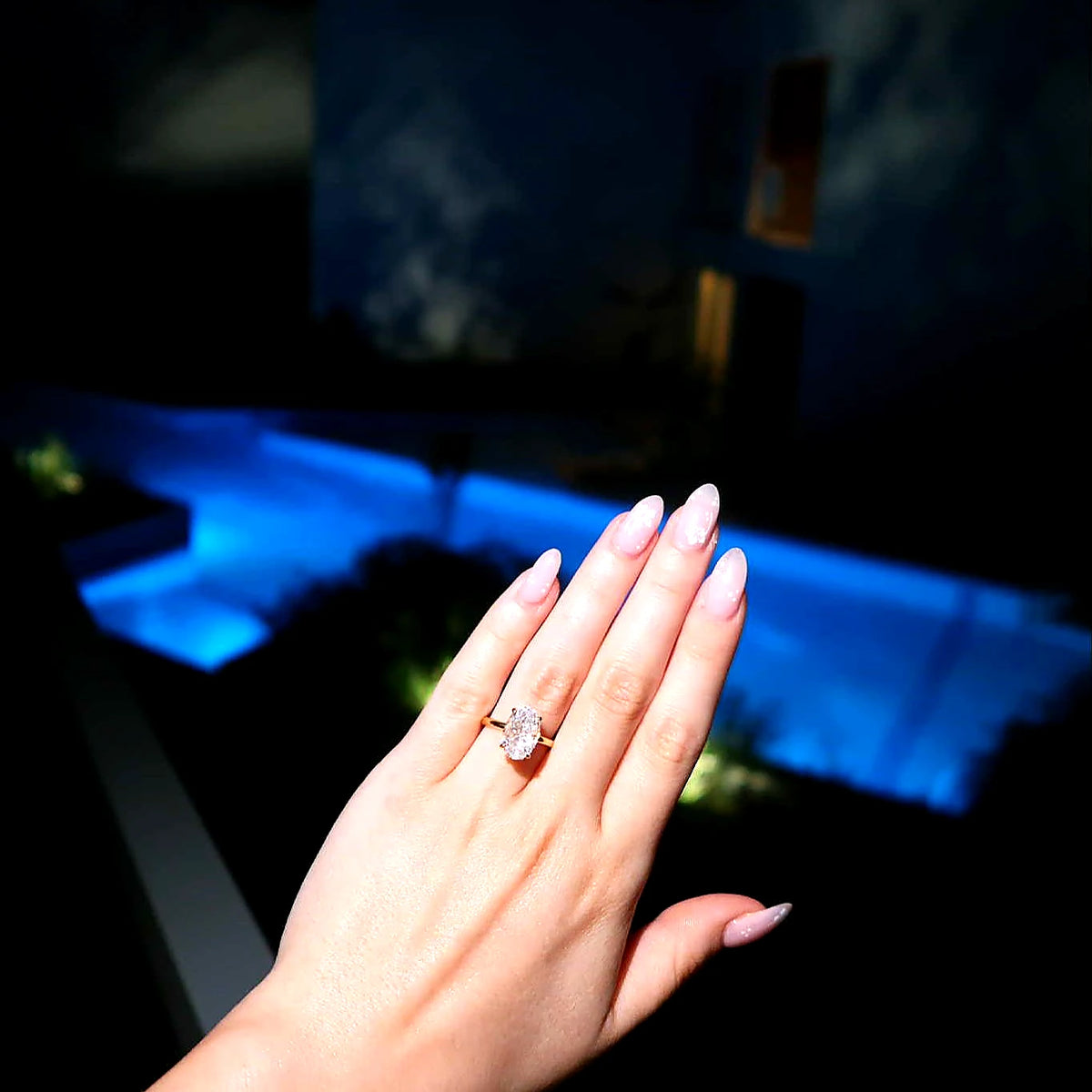 Hand wearing a 3.5ct gold oval ring with a blurred background