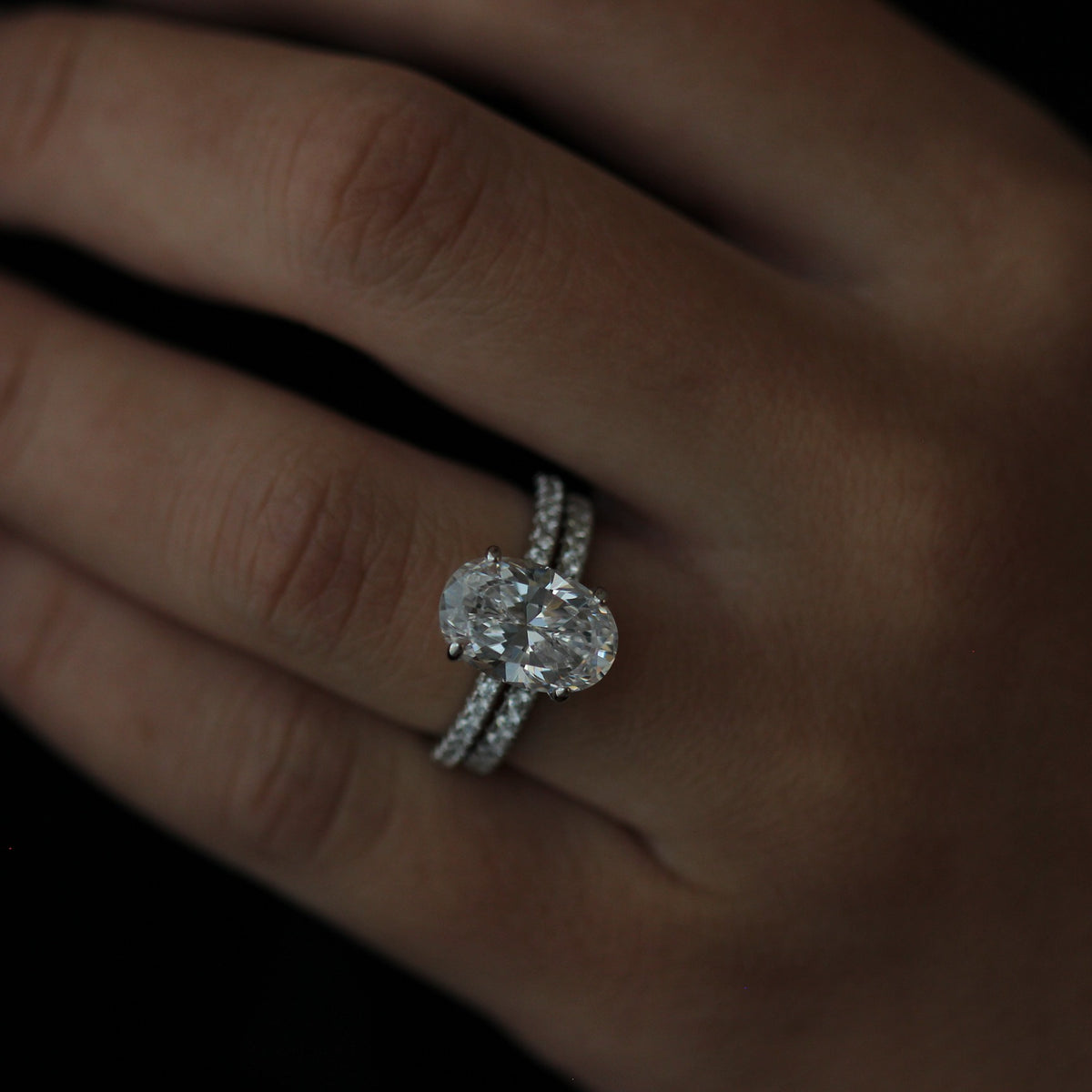 3.5ct oval ring on a finger with a dark background