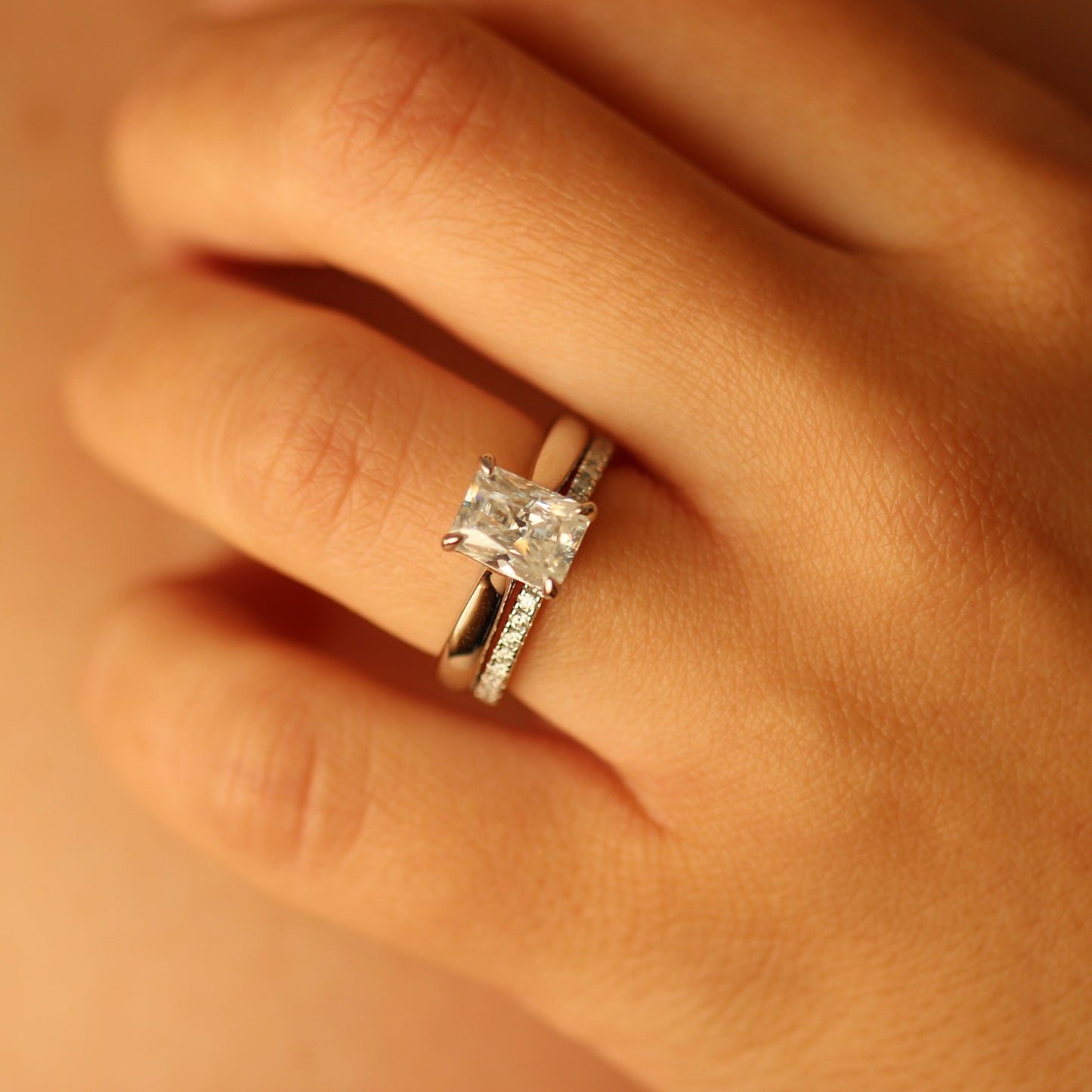 2ct radiant moissanite ring on hand with moissanite pave band