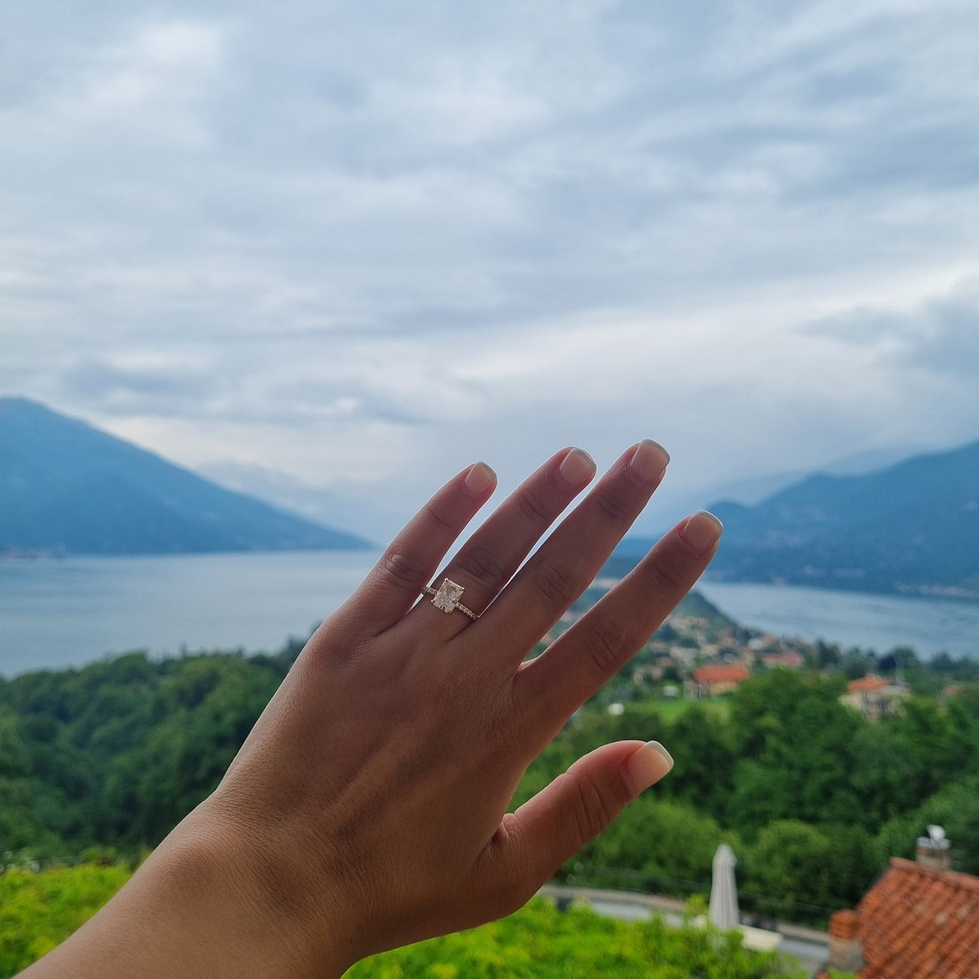 Gold radiant cut rectangle ring on hand in Lake Como