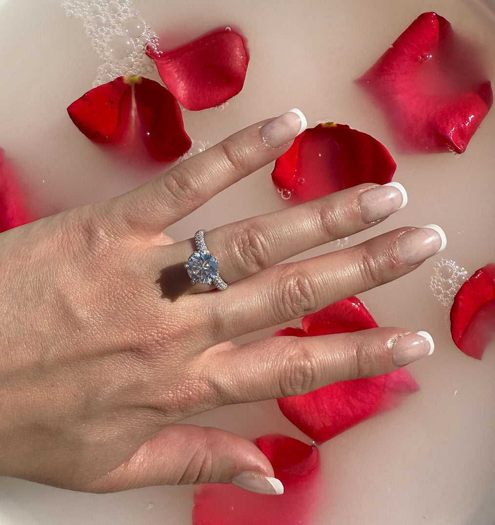 round stone on silver band with tiny cz stones on it on top of milk bath with rose petals