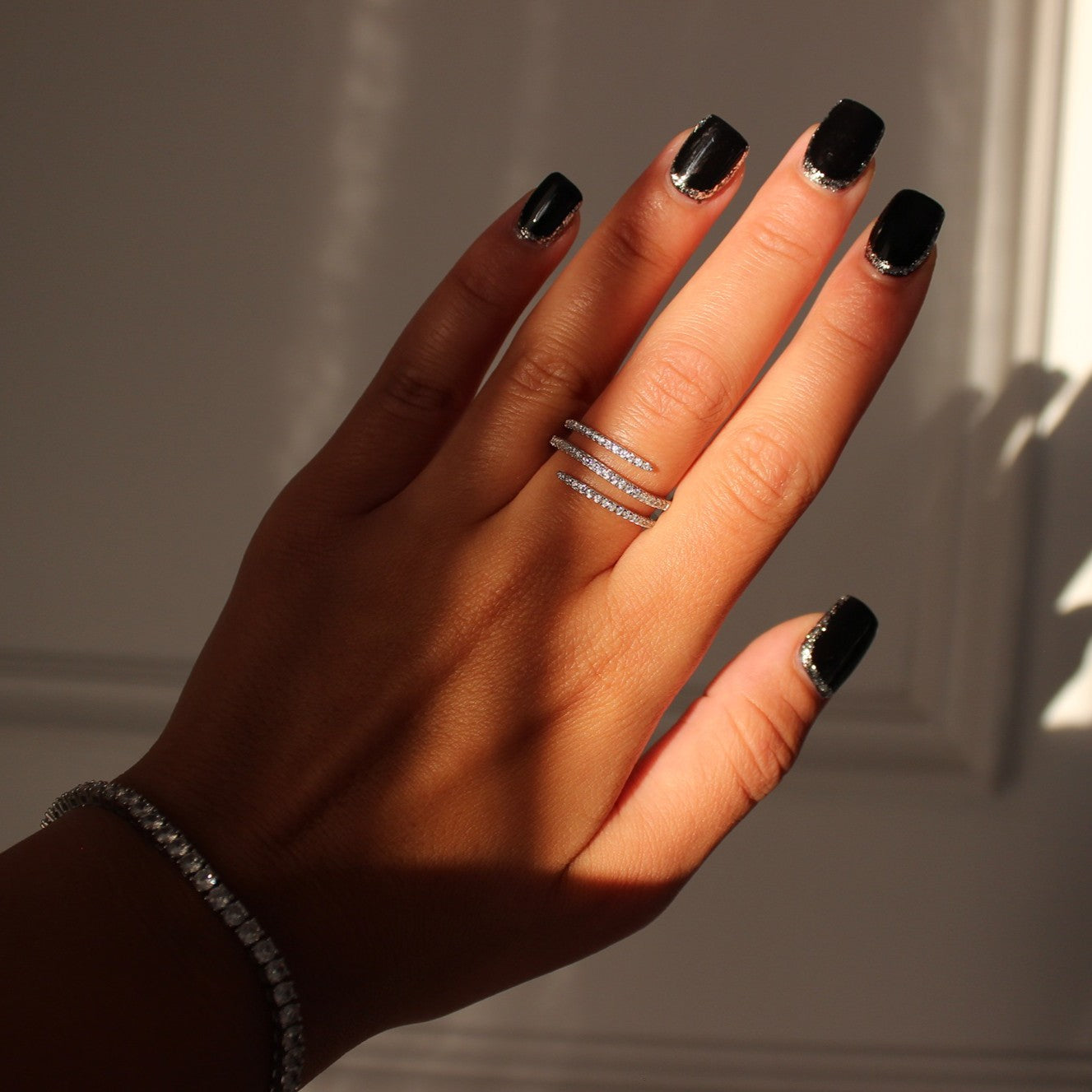 Cairo spiral ring in silver on hand with silver tennis bracelet