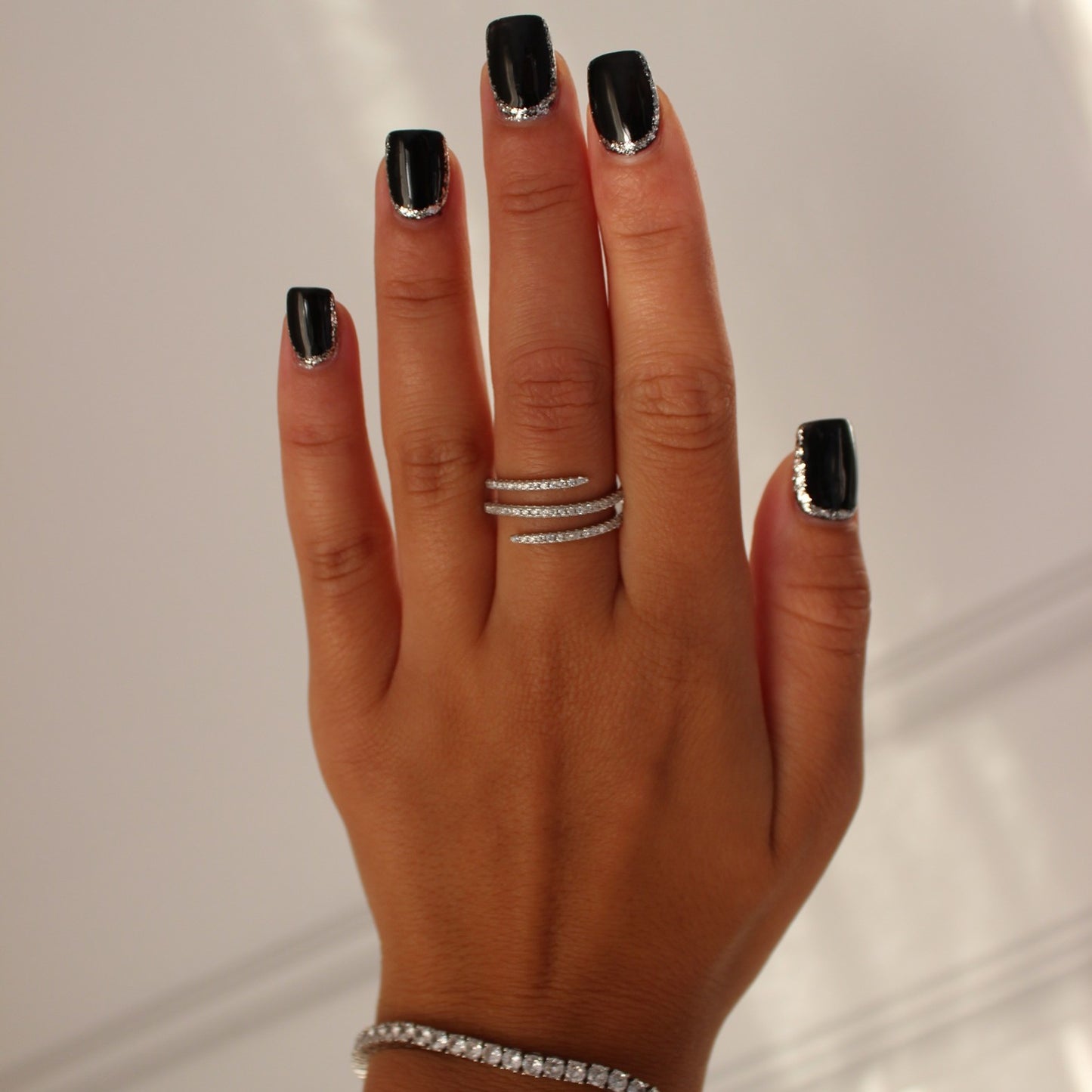 Cairo spiral ring in silver on hand with silver tennis bracelet