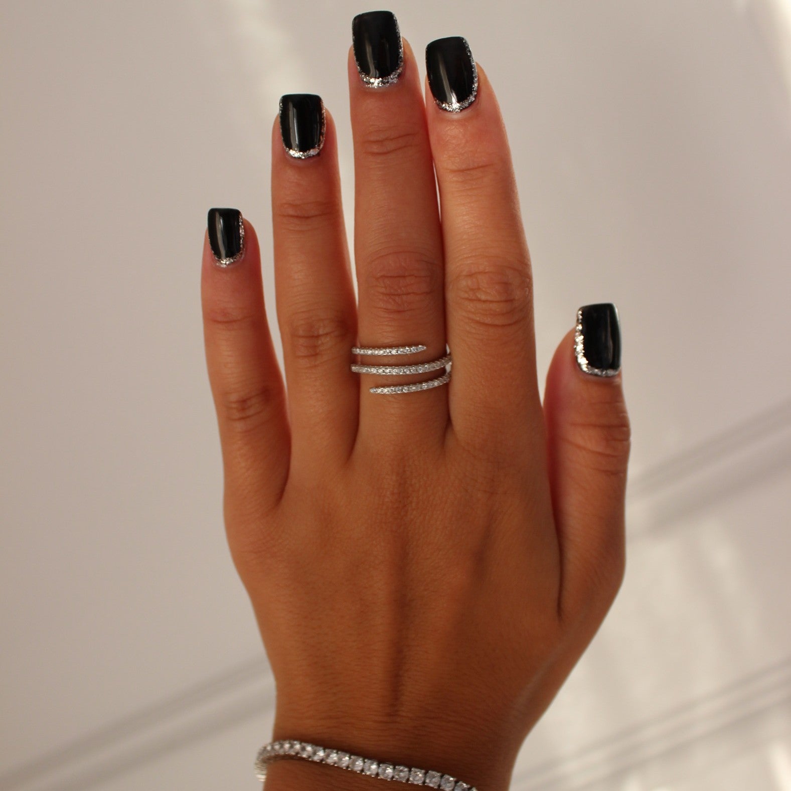 Cairo spiral ring in silver on hand with silver tennis bracelet