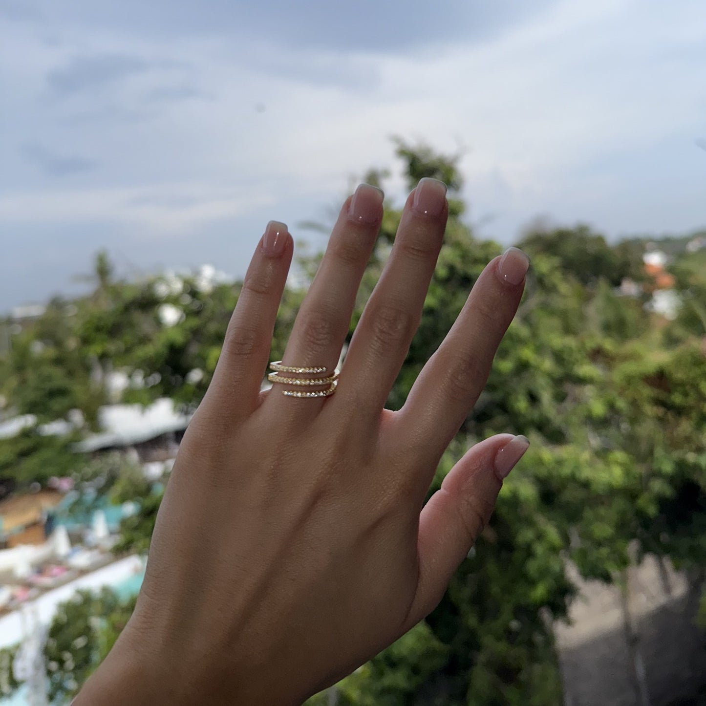 Hand with a spiral ring against a blurred outdoor background