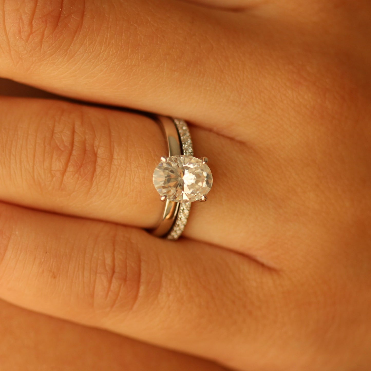 Oval cut moissanite ring on hand with pave band