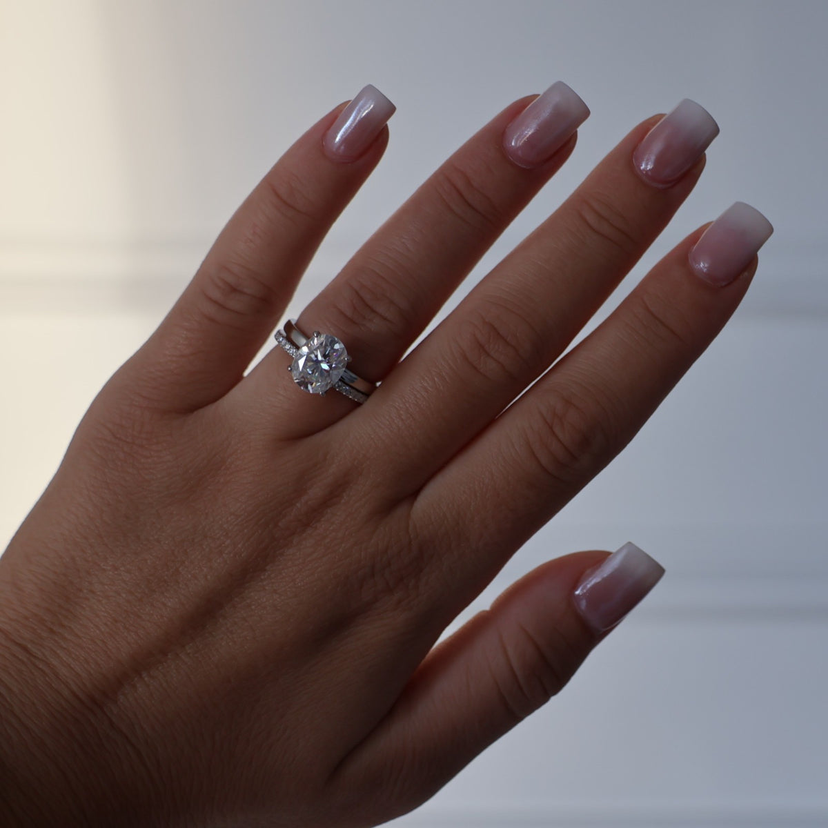 3ct oval moissanite ring on hand with silver pave band
