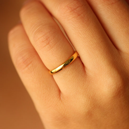 18k Gold vermeil ring on a person's finger with a warm brown background