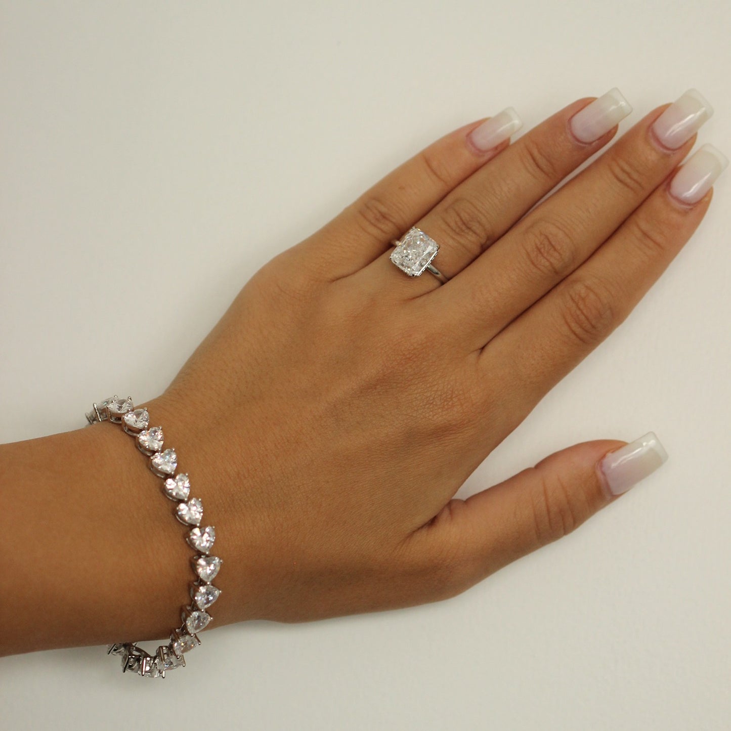 Heart tennis bracelet on hand with fake engagement ring