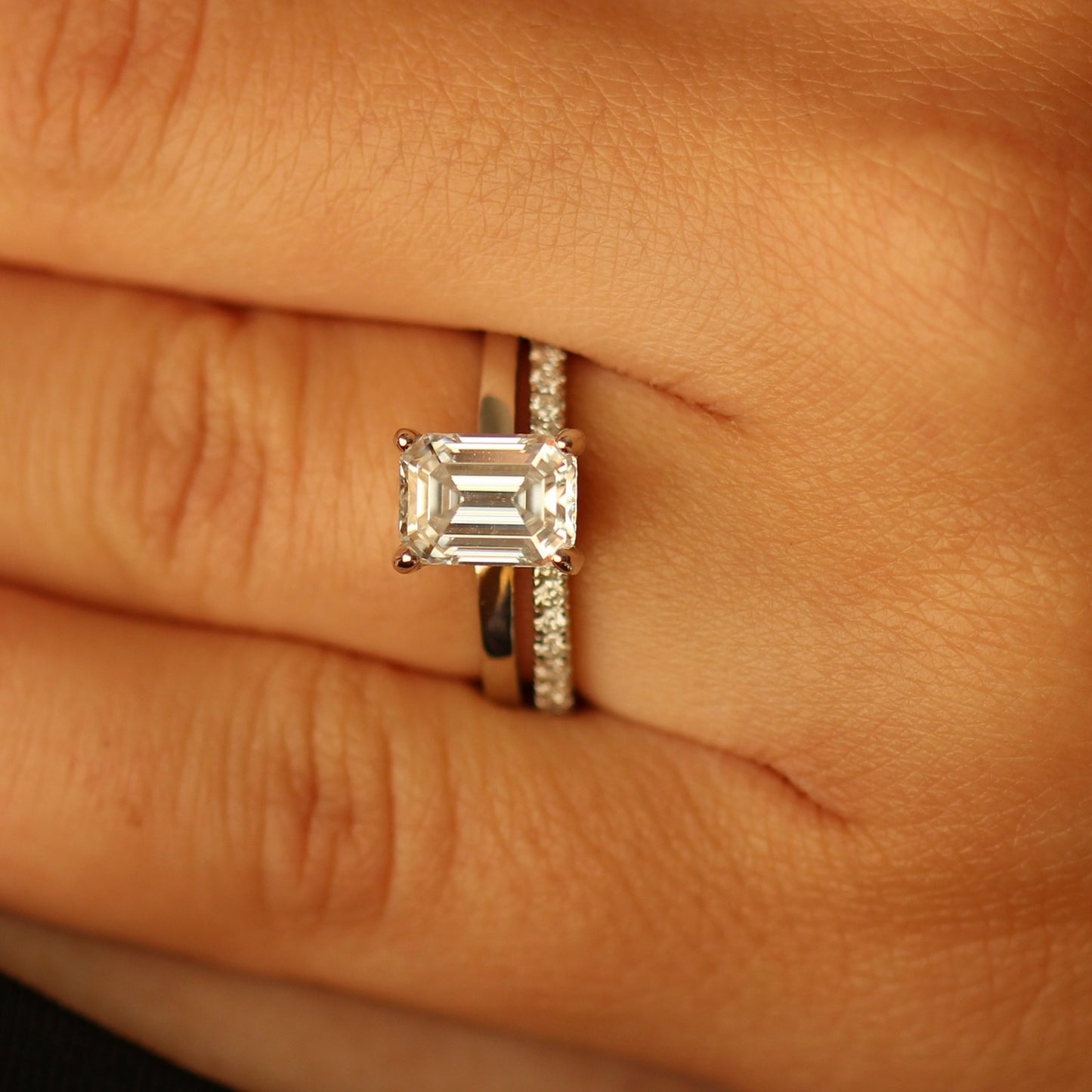 Emerald cut moissanite ring with pave band on hand