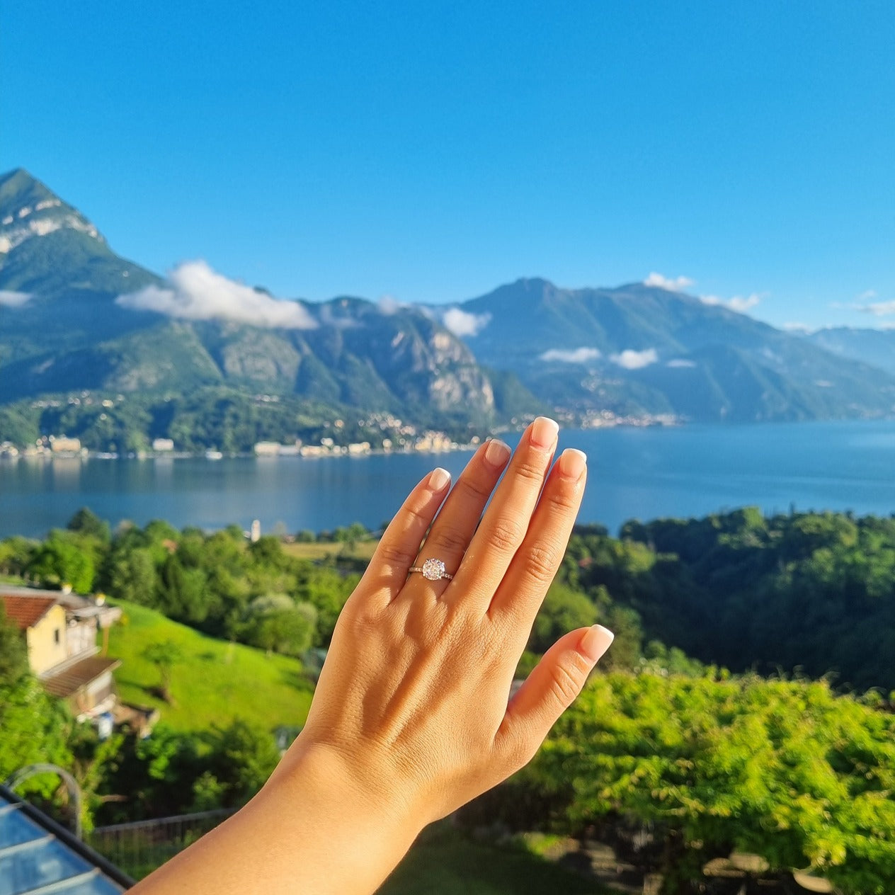Round cut ring on hand in front of Lake Como