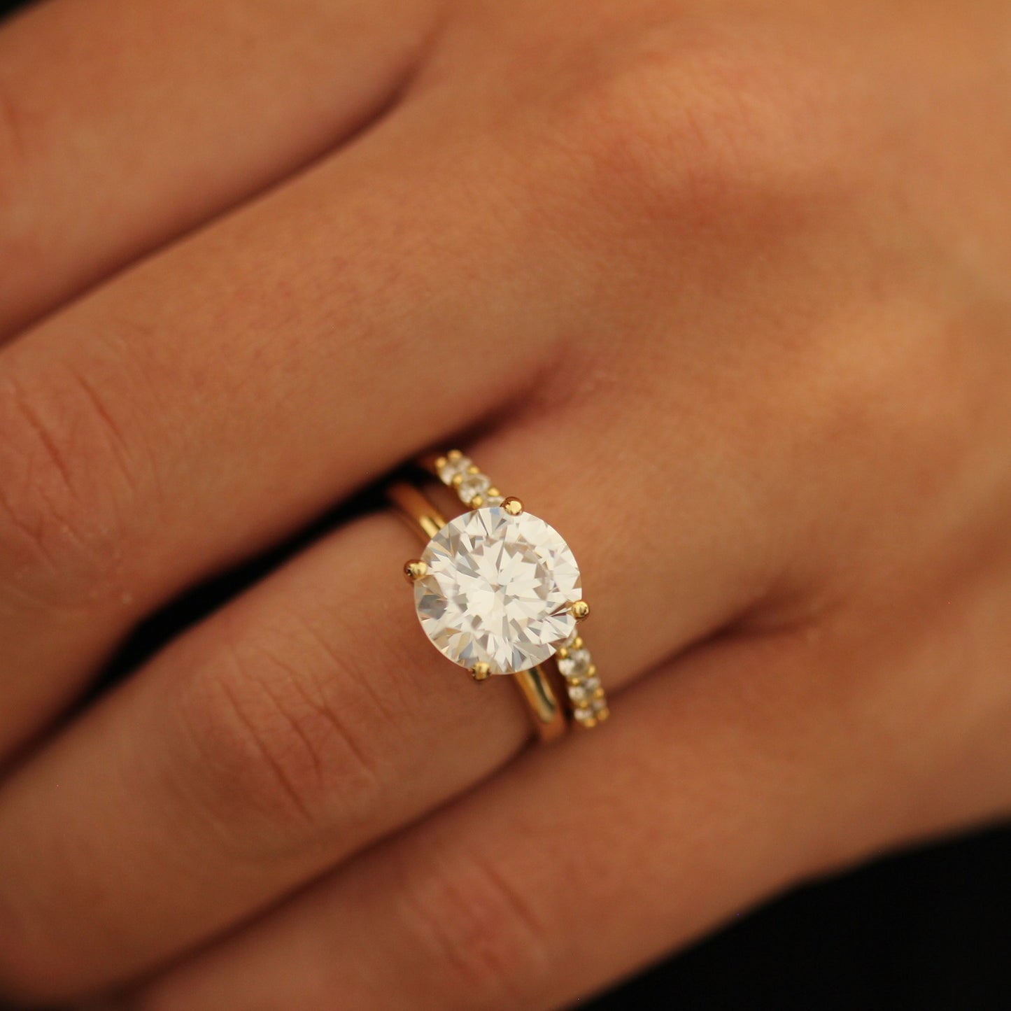 4ct round cut ring with stacking band on a person's finger