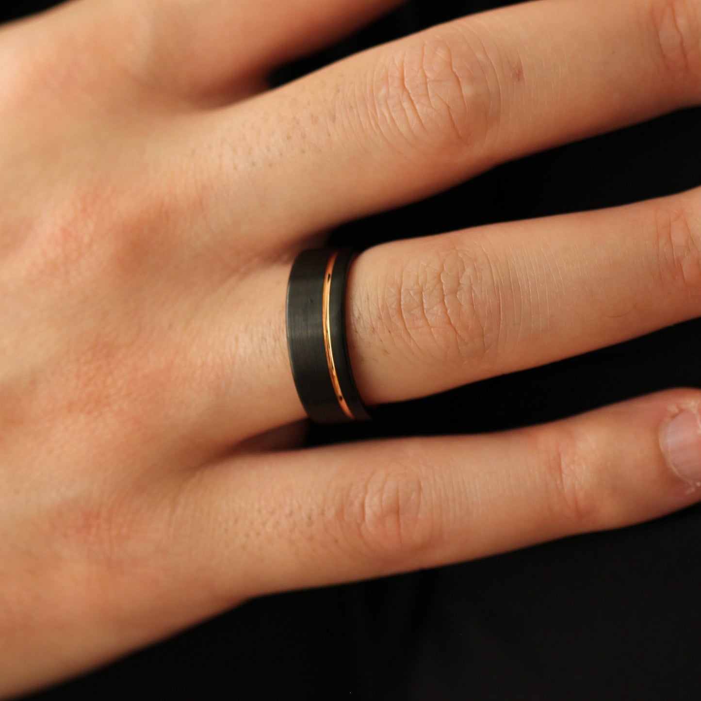 Men’s black wedding band with a rose gold offset line accent
