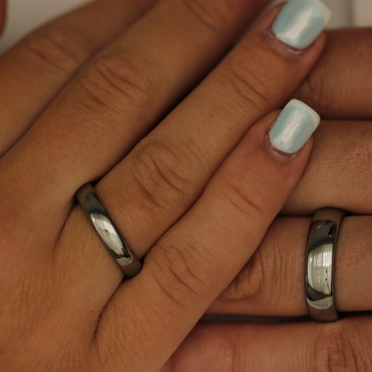 Close-up of hands with polished silver rings and light blue nail polish