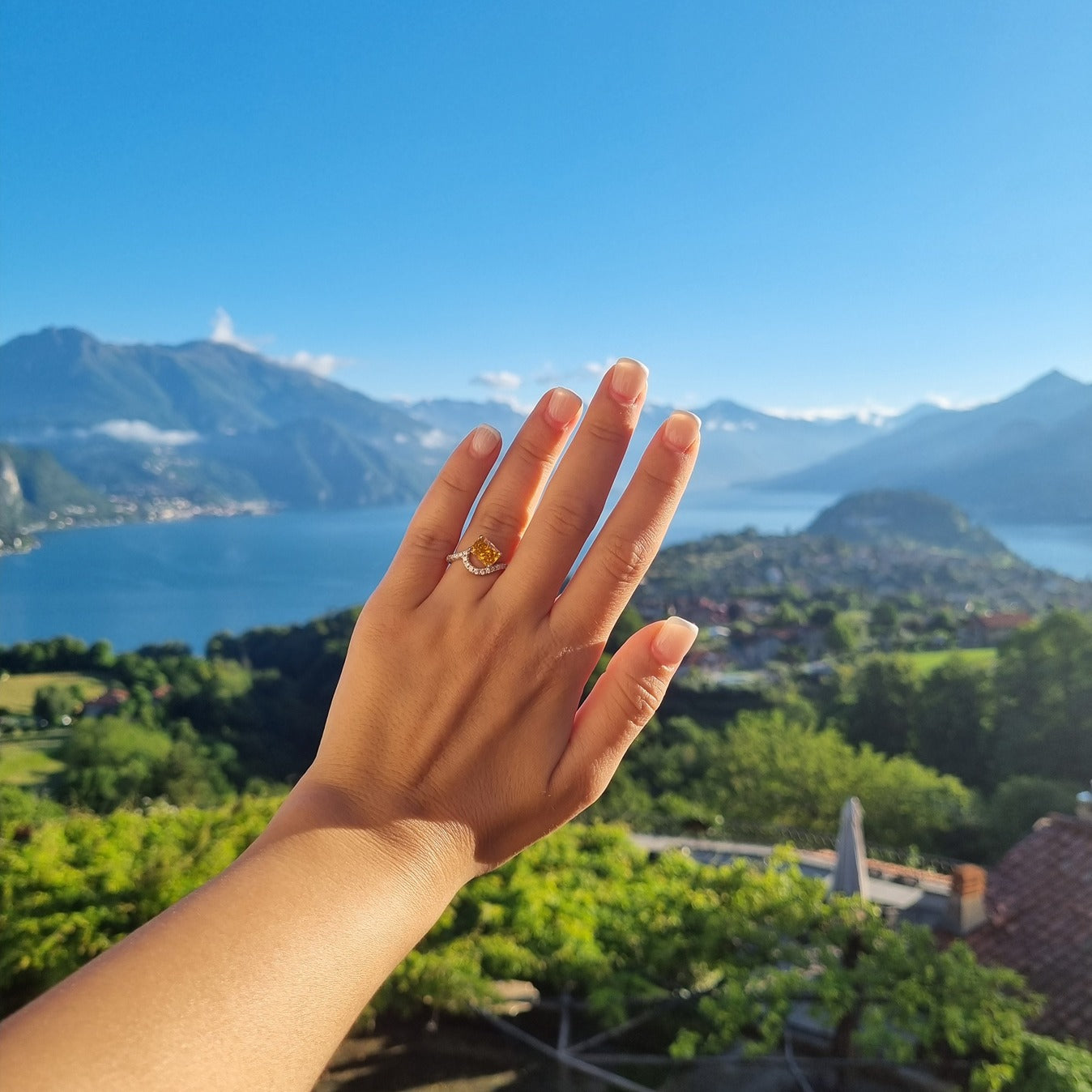 Yellow stone ring on hand in front of Lake Como