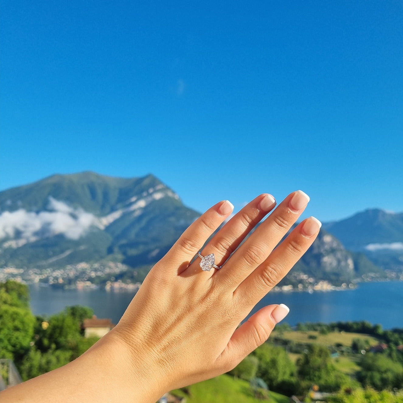 Silver pear ring on hand in front of Lake Como