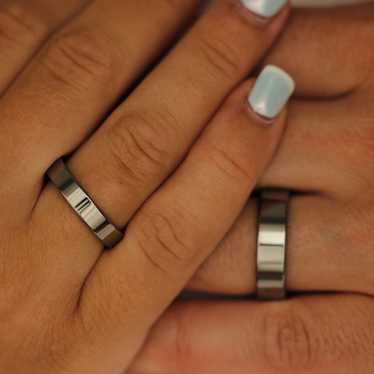 Close-up of two hands with silver rings on fingers