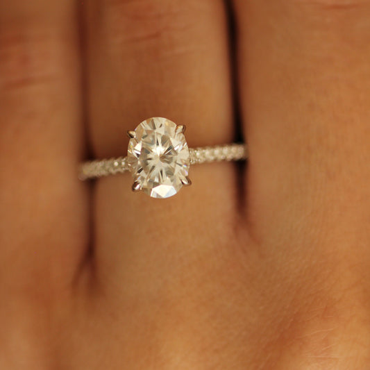 Oval moissanite ring with pave band on a finger