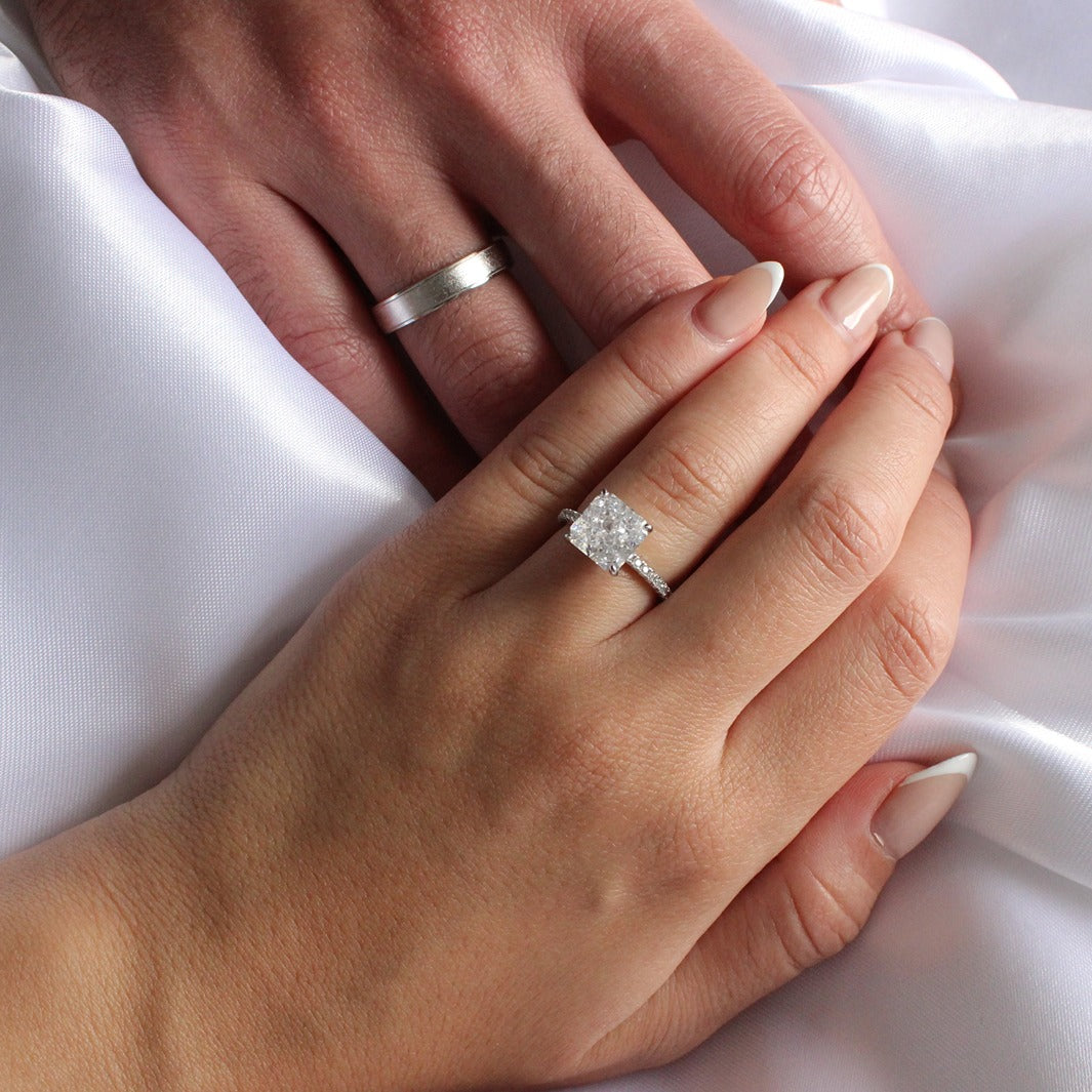 Silver mens ring and womens silver ring on hands in front of white background