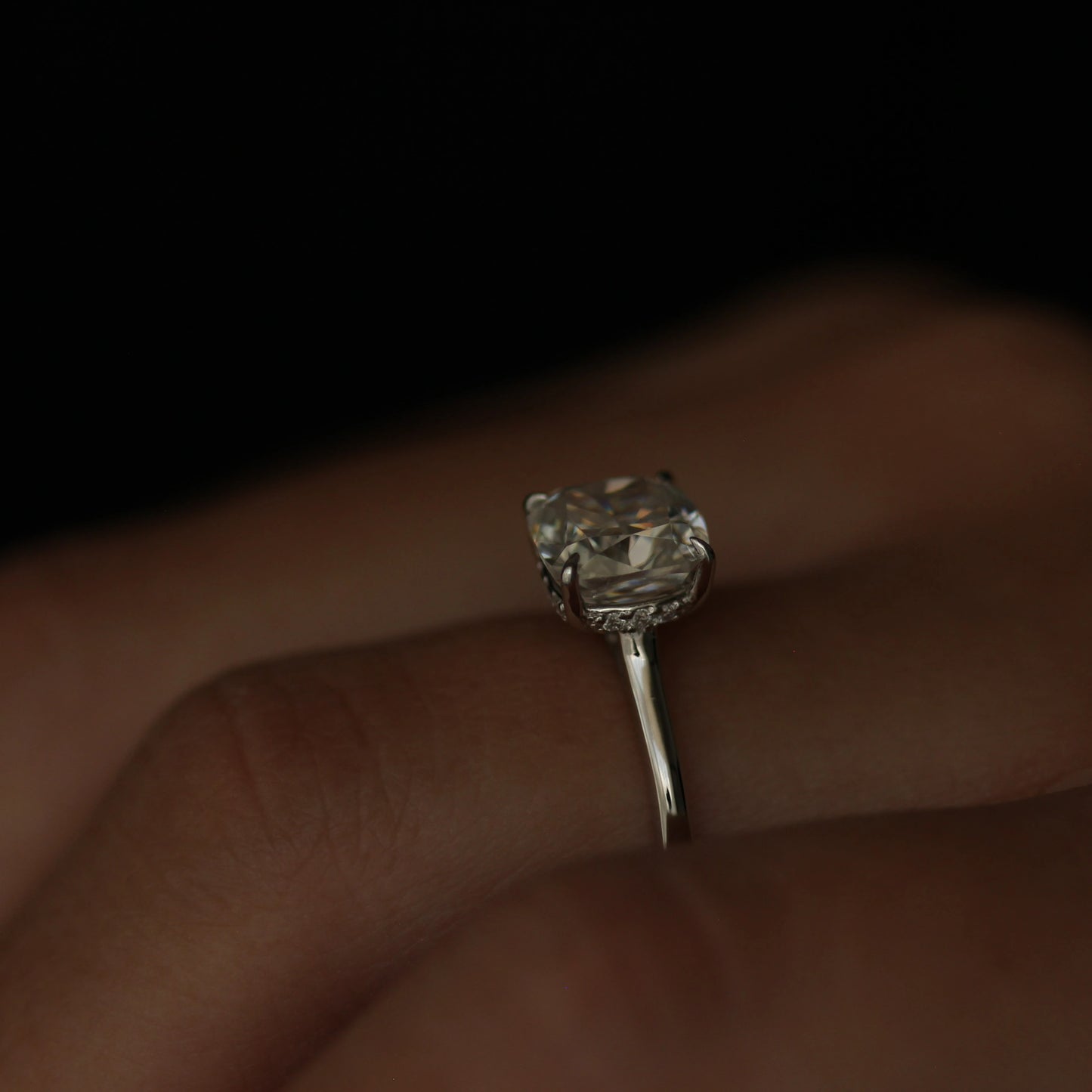 Side view of cushion cut moissanite engagement ring with hidden halo in silver