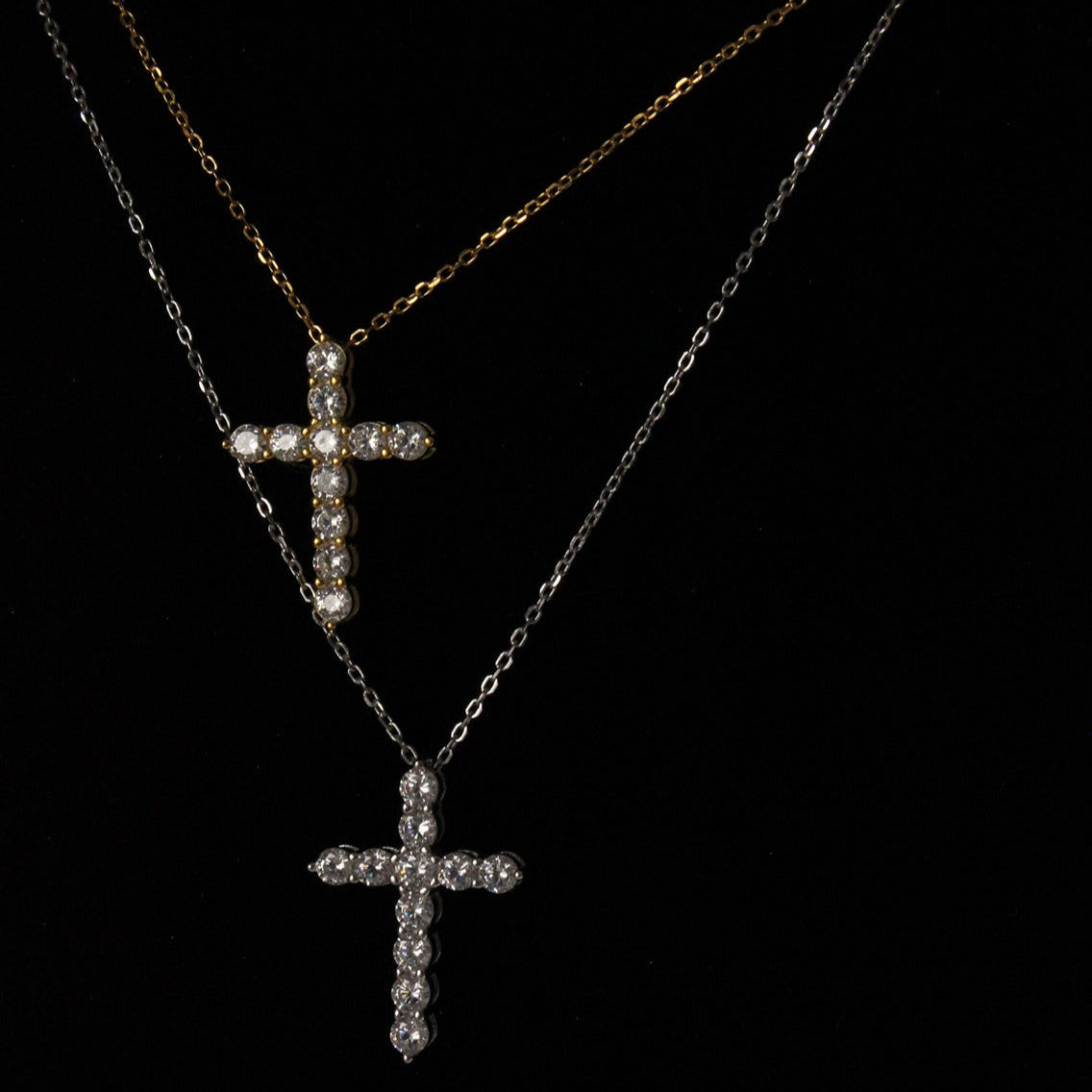 gold cross necklace next to a silver cross necklace