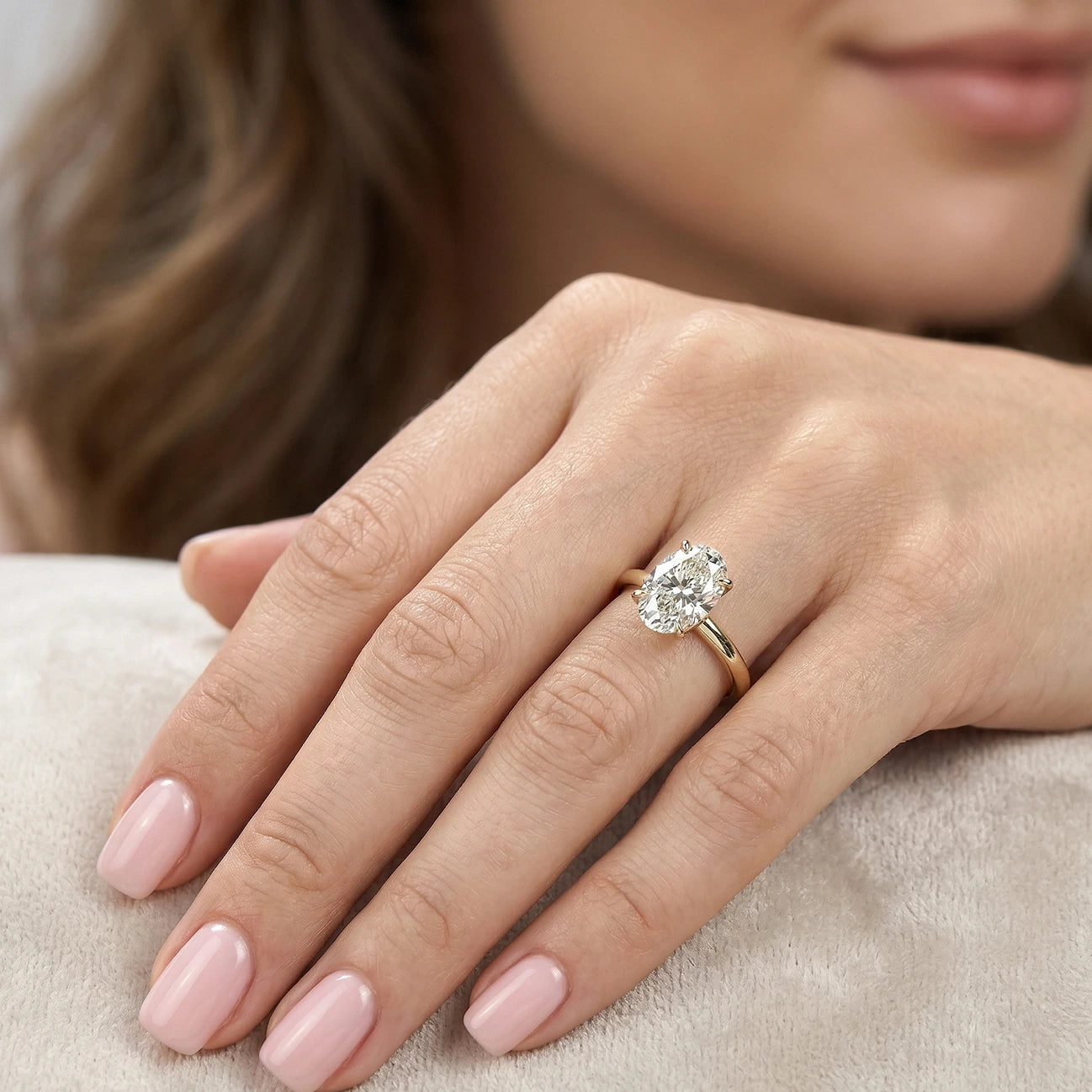 Gold oval lab grown diamond engagement ring on model's hand