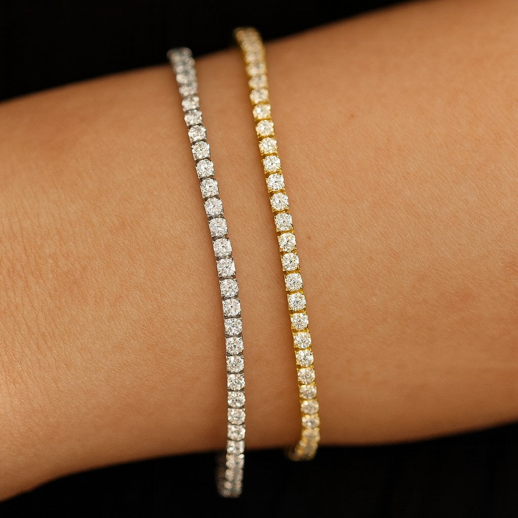 Gold tennis bracelet and silver tennis bracelet on wrist against black background