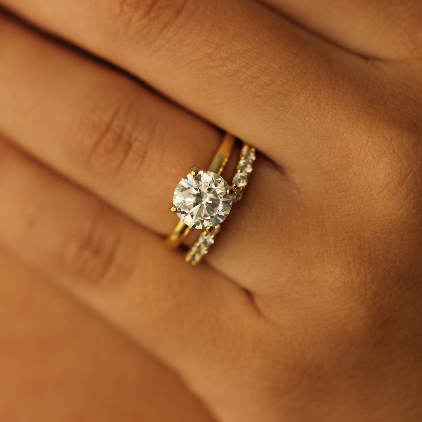 2 ct round gold engagement ring and gold open ring on hand