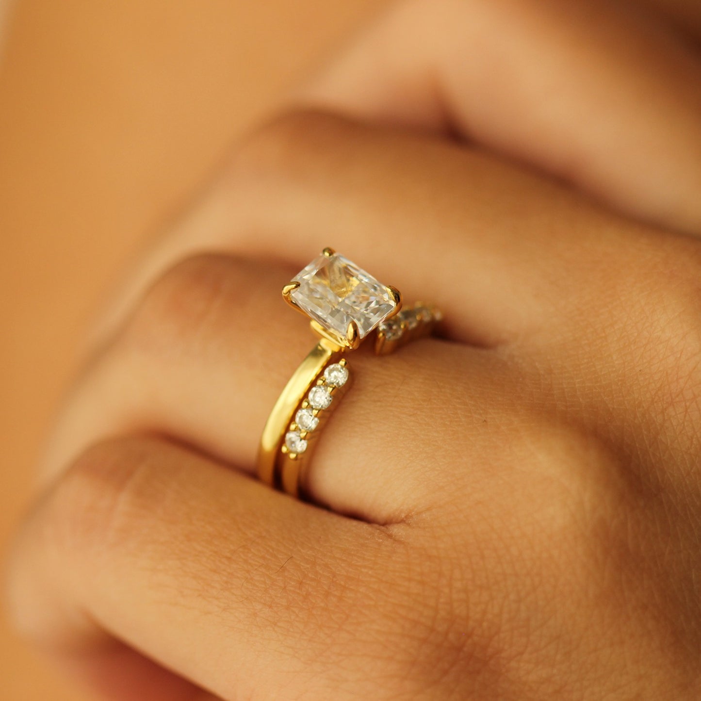 plain gold ring with 2 carat rectangle cubic zirconia centre stone on hand with gold open ring