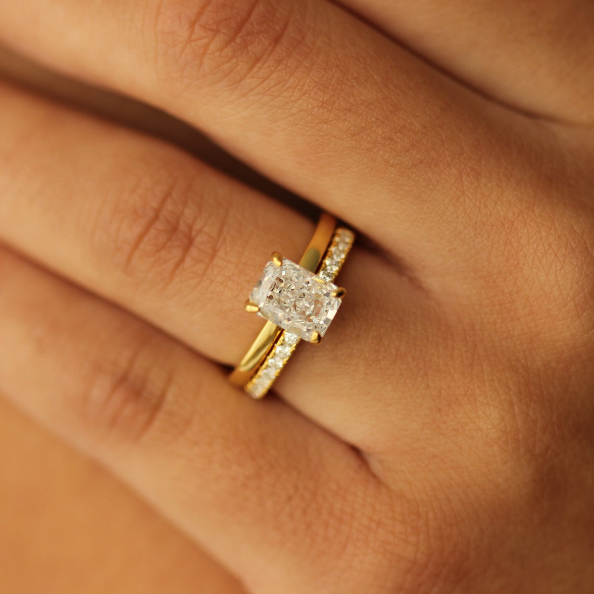 plain gold ring with 2 carat rectangle cubic zirconia centre stone on hand with half pave ring
