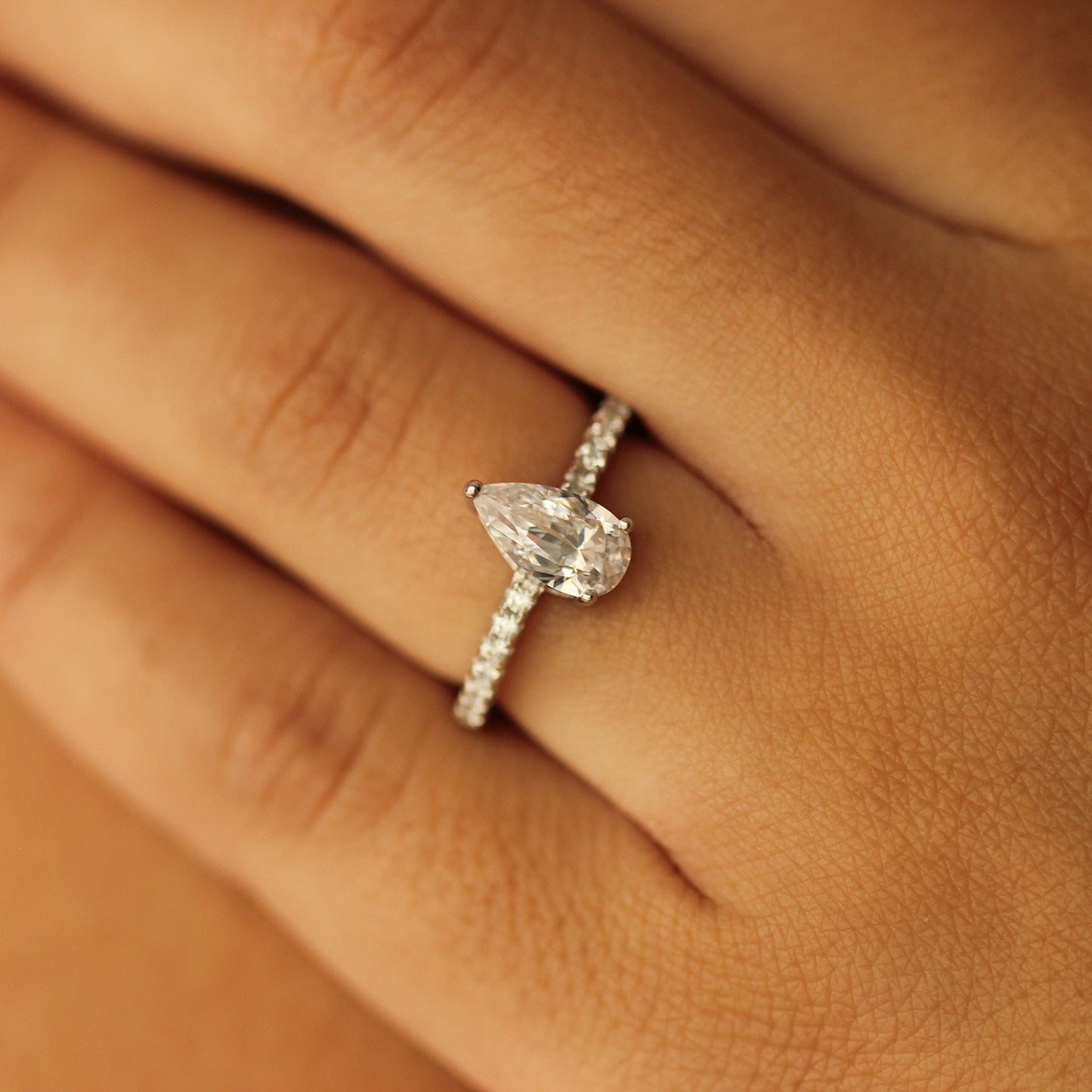 pear ring in silver on half pave band with a slim centre stone on hand