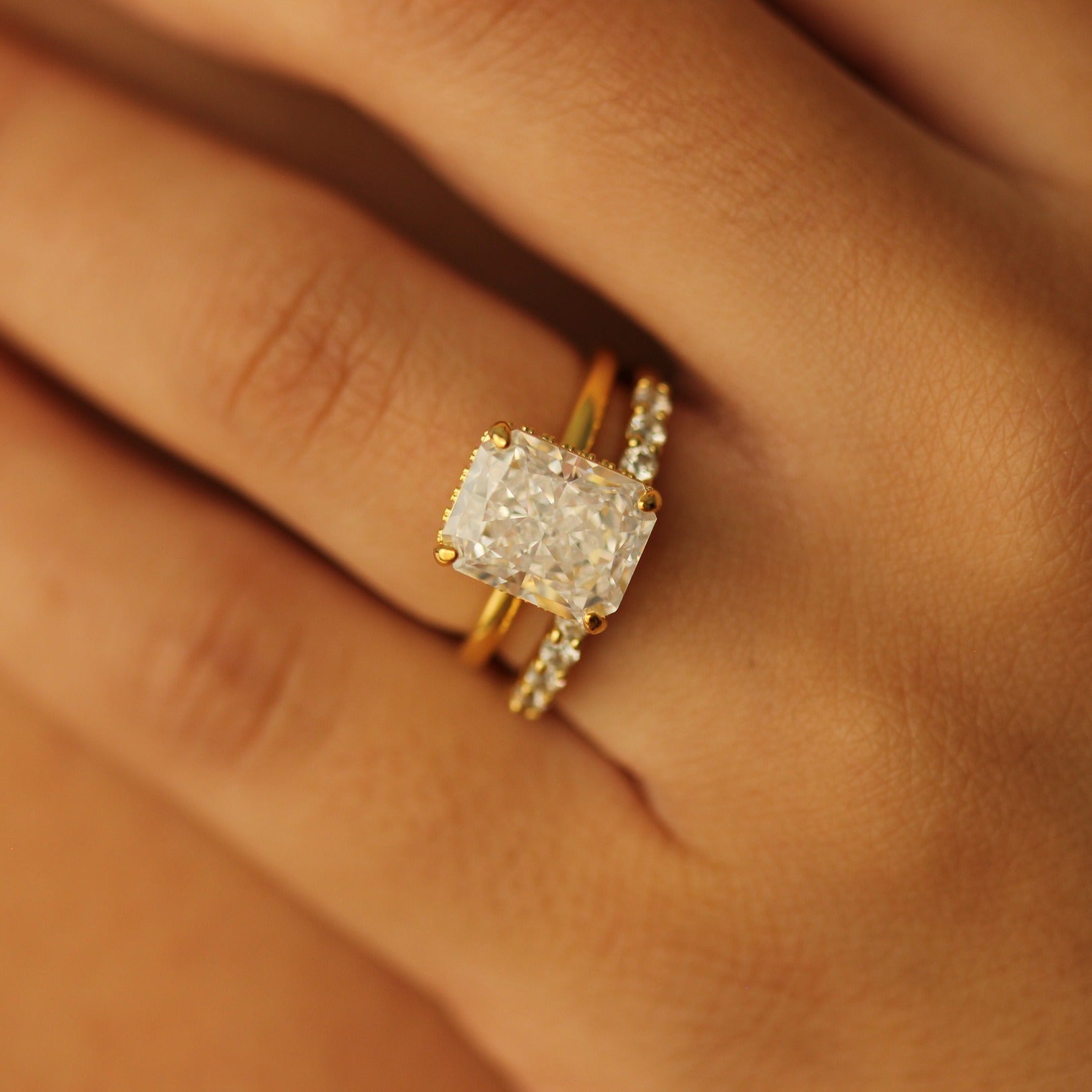 radiant cut gold ring with 4 carat centre stone with gold open ring on hand