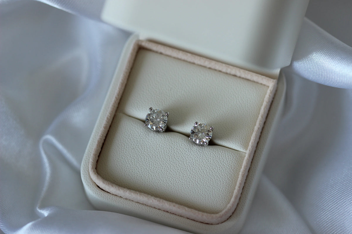 2tcw Moissanite earrings in a beige jewelry box on a white fabric background