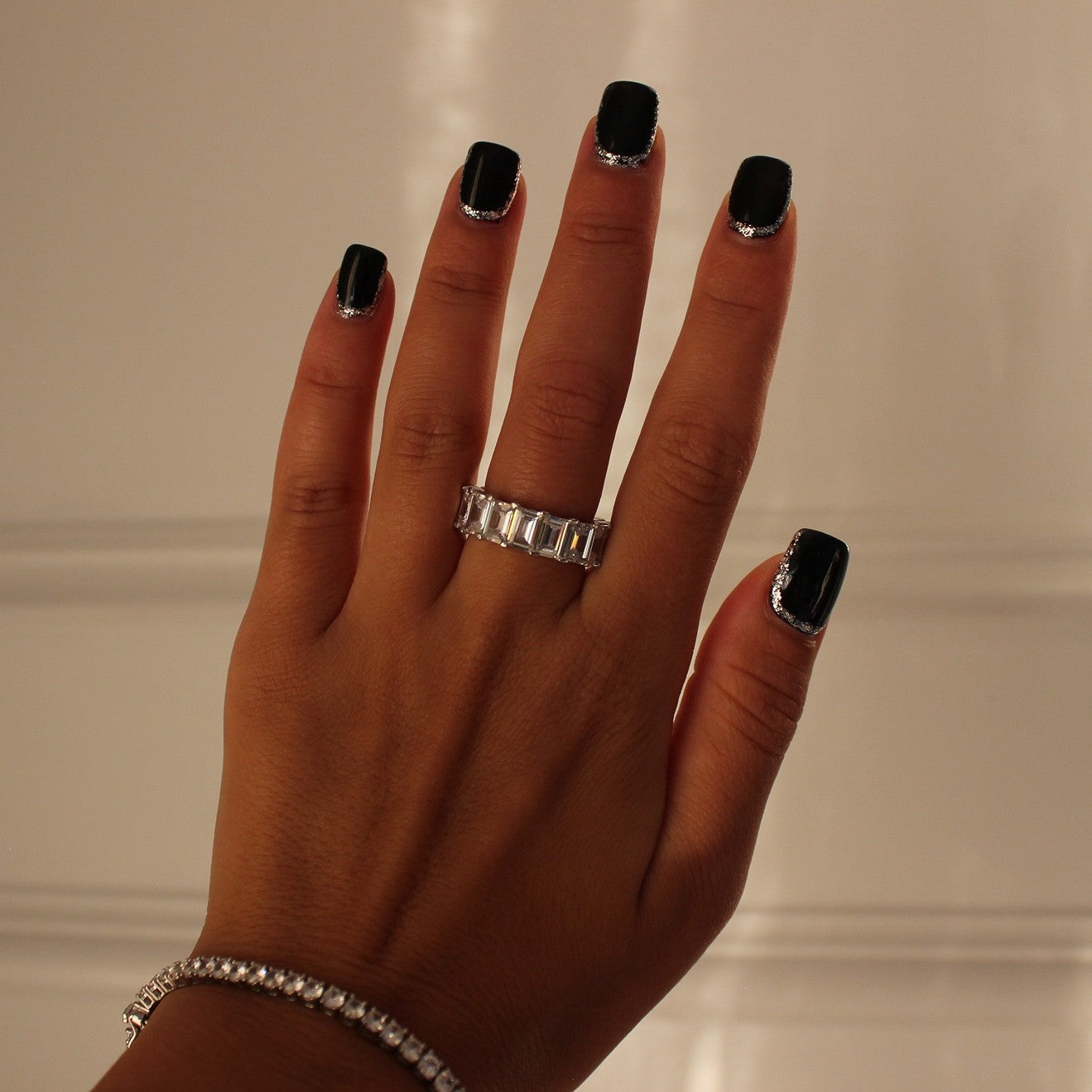 Rectangle silver stacker ring on hand with silver tennis bracelet