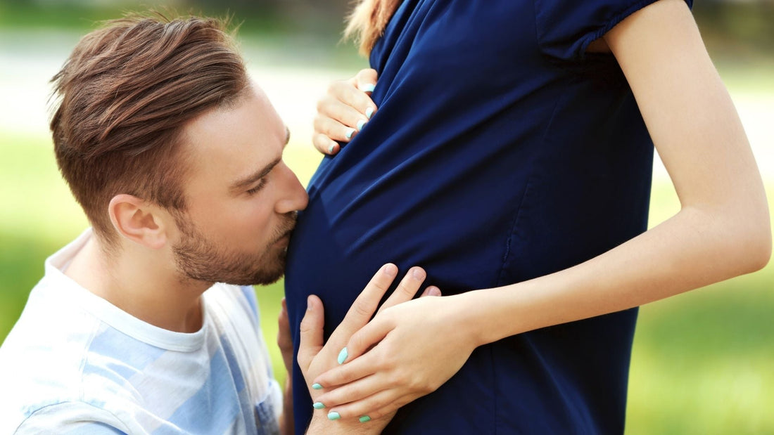 guy kissing his pregnant wife on stomach and gifting her a push present