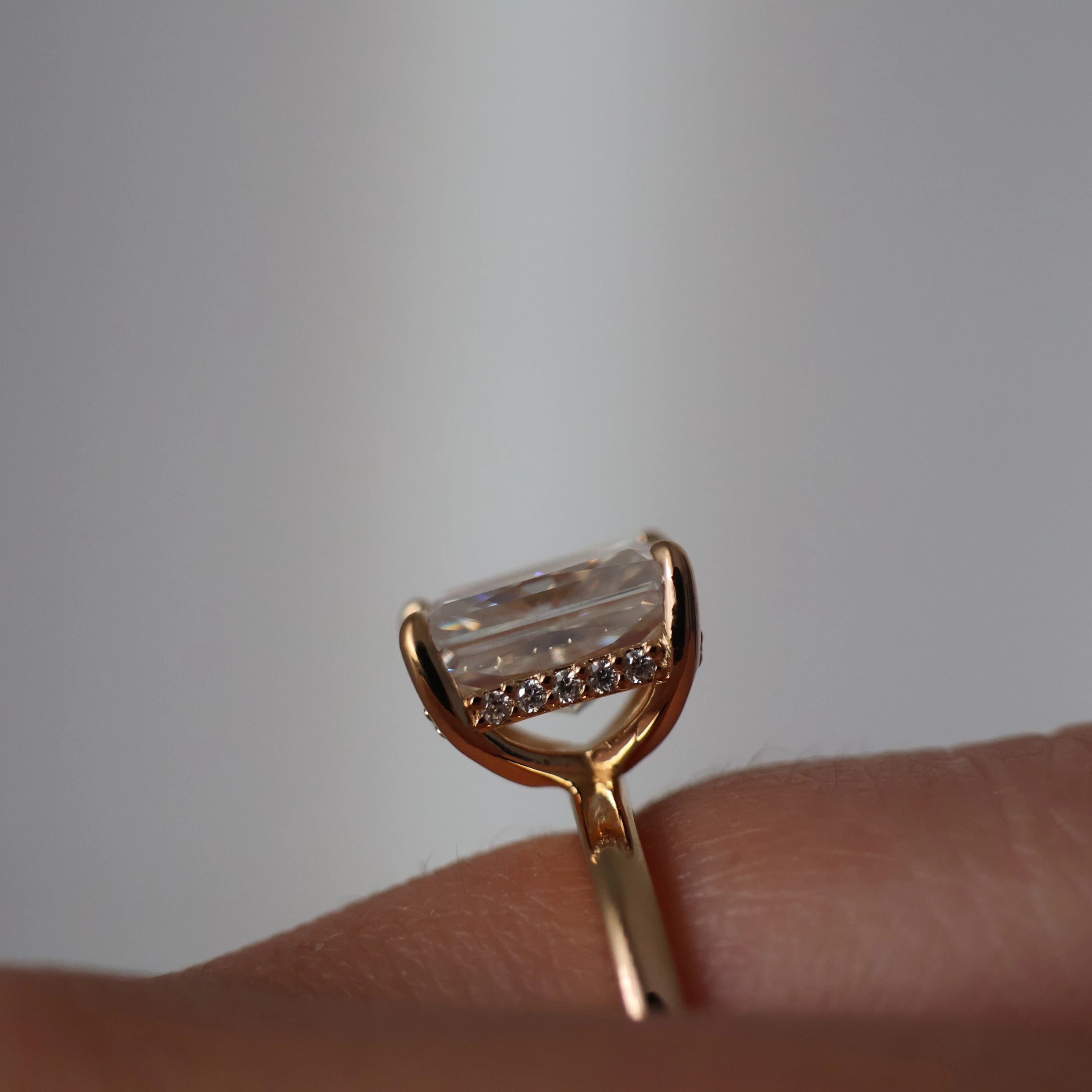 Side view of a 3 carat radiant cut moissanite ring in 14k gold filled with hidden halo