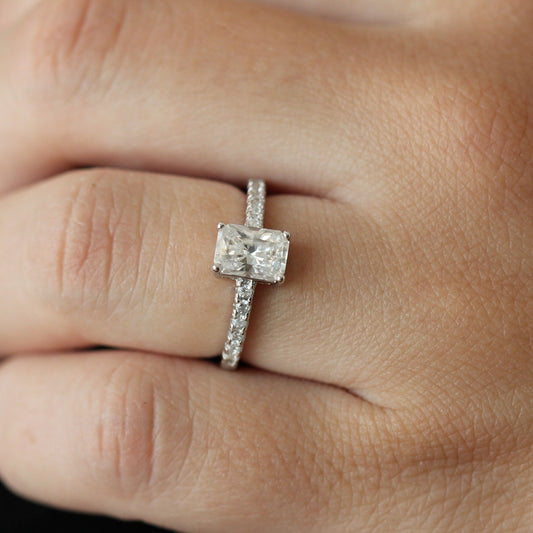 Close up view of a 1 carat radiant cut moissanite ring with a pavé set band