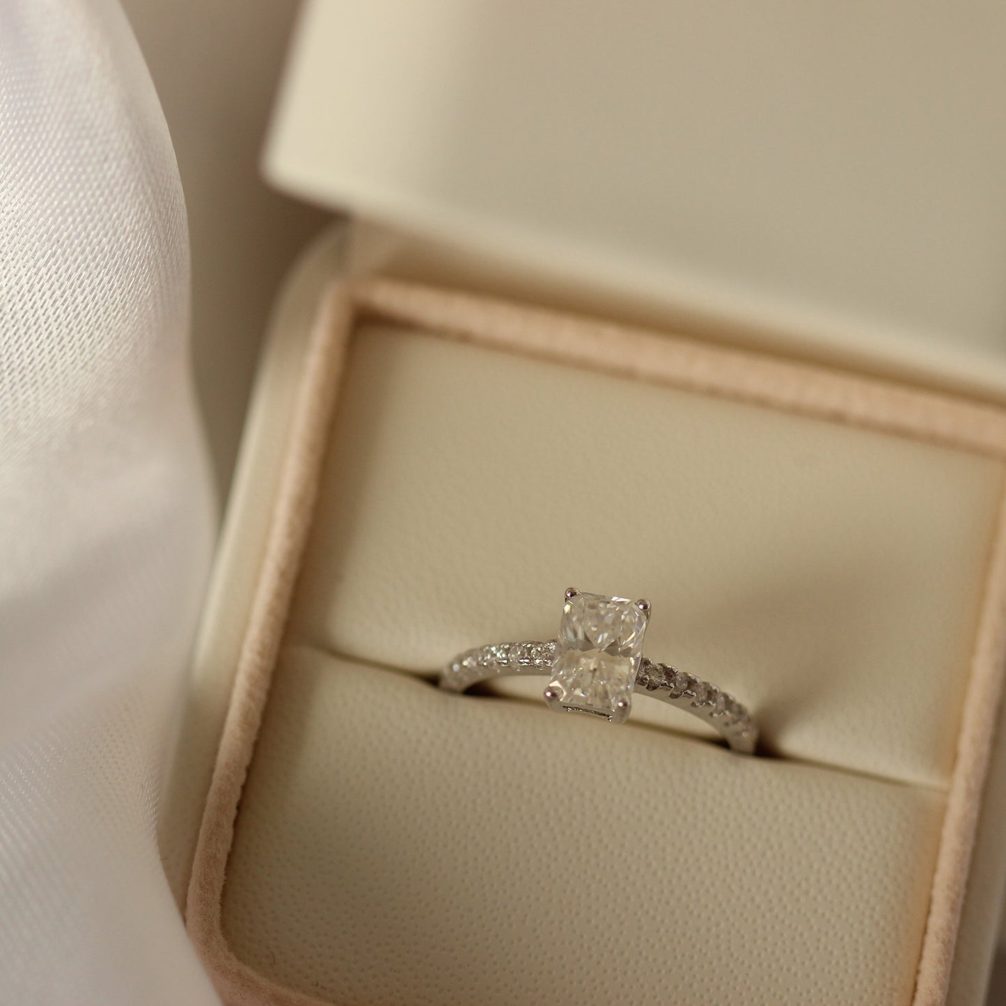 1 carat radiant cut moissanite ring with a pavé band in proposal ring box