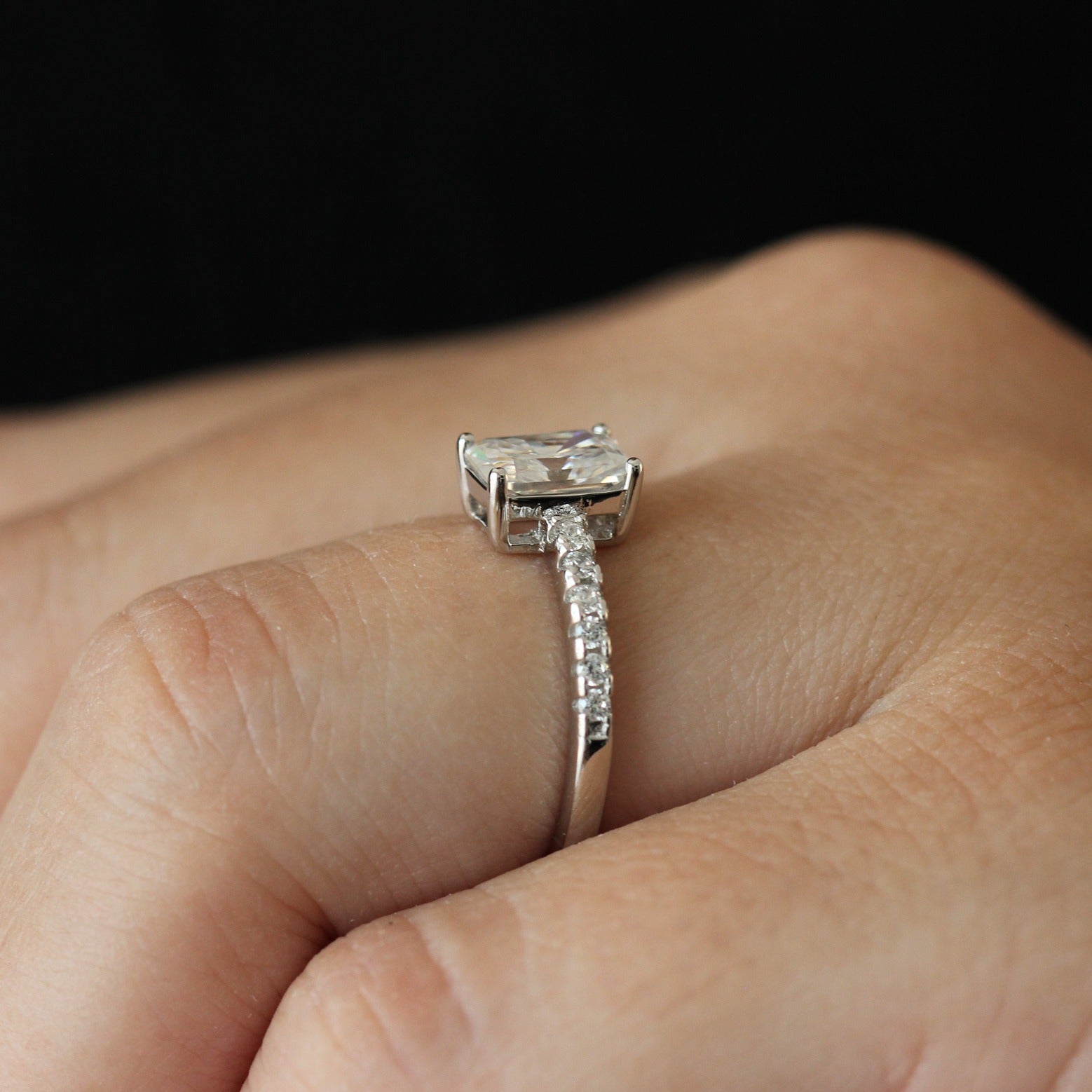 Side view of a 1 carat radiant cut moissanite ring with a pavé set band