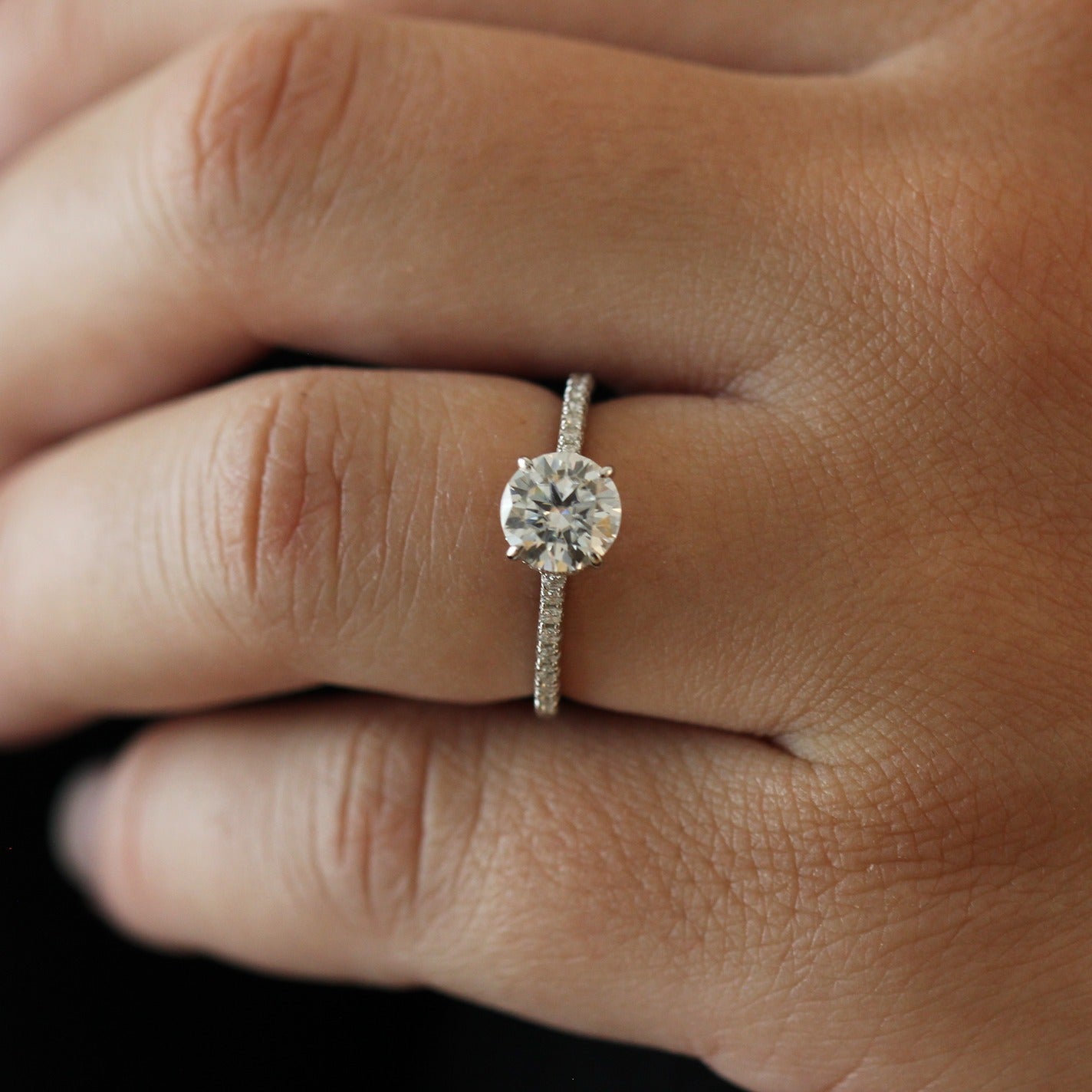 Close up of a 1 carat round moissanite ring with a pavé band