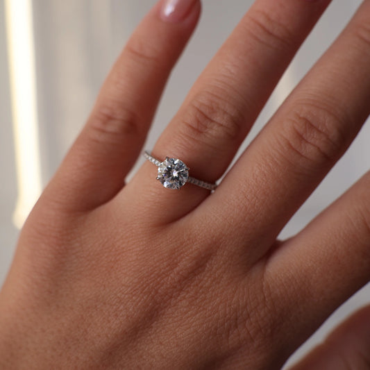 Close up of a 1 carat round moissanite ring with a pavé band