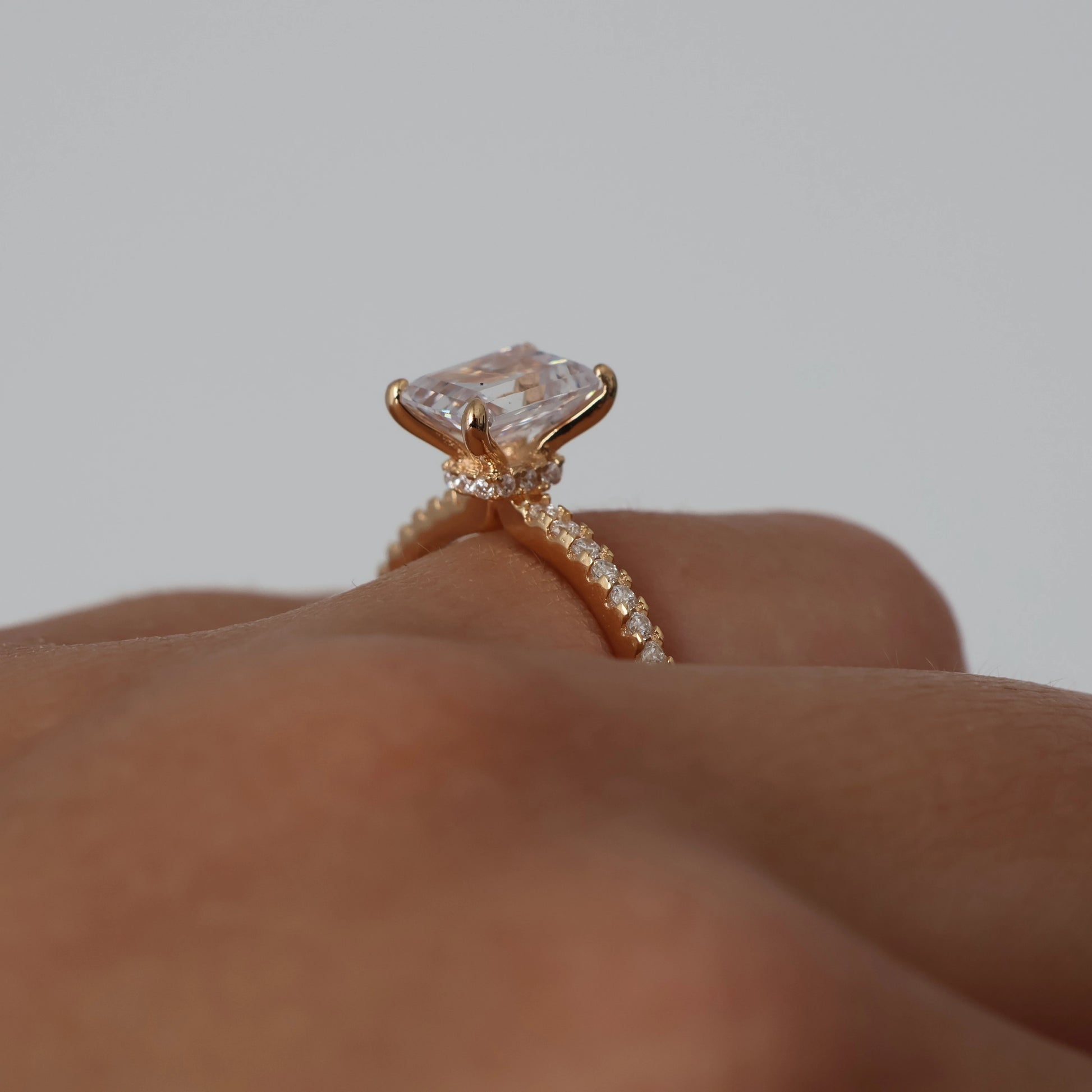 2 ct emerald cut cubic zirconia ring with a hidden halo and pavé band in a champagne gold finish