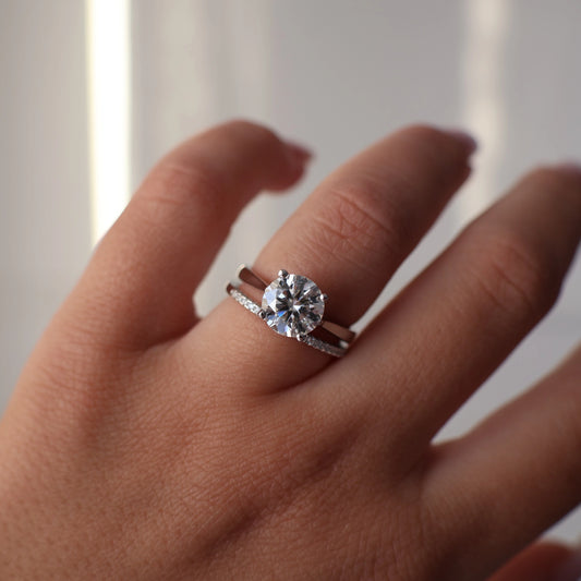 Round cut moissanite ring on hand with half pavé band