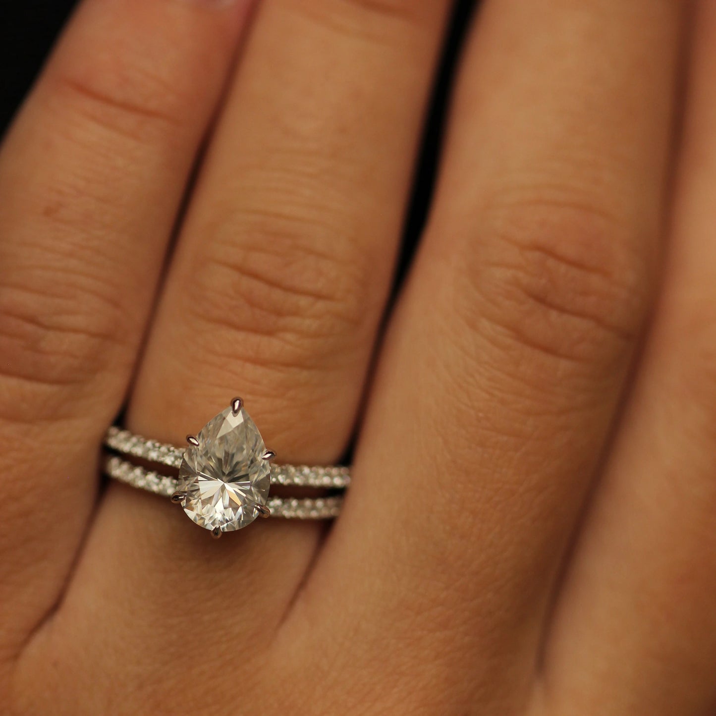 2 ct pear cut moissanite engagement ring and moissanite pave band on hand