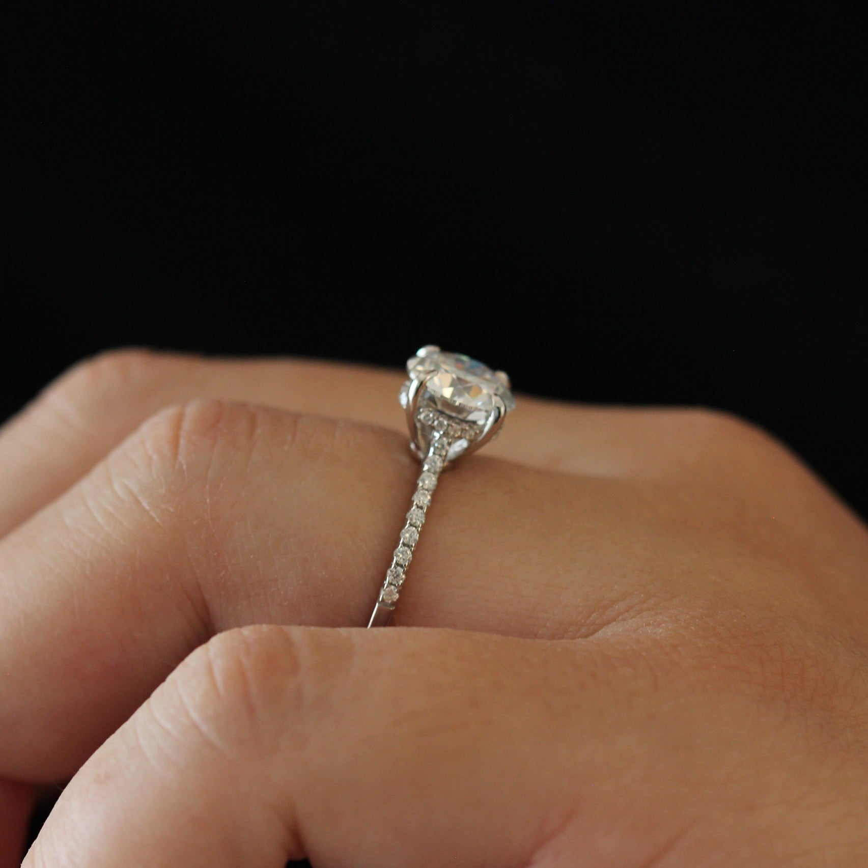 Side view of a 2 carat round moissanite ring with a pavé band