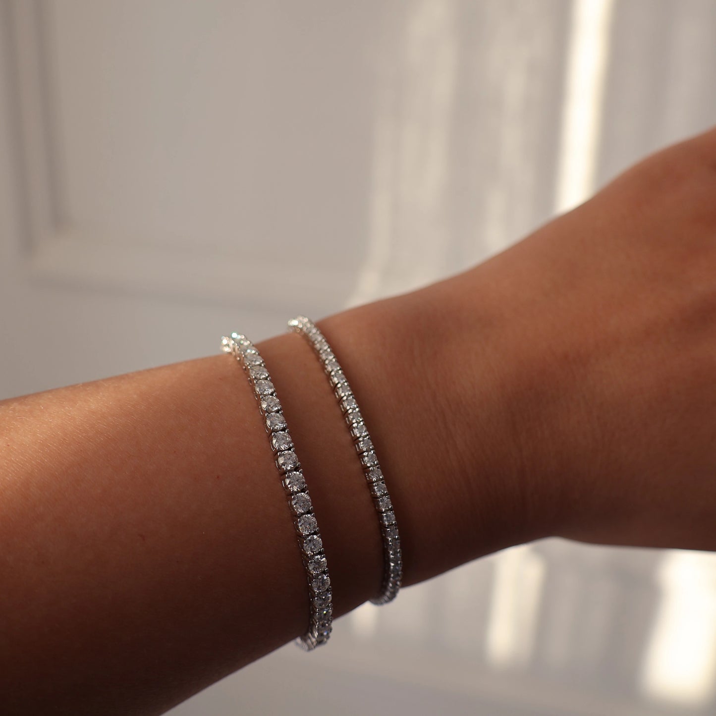 2mm silver moissanite tennis bracelet next to 3mm moissanite tennis bracelet